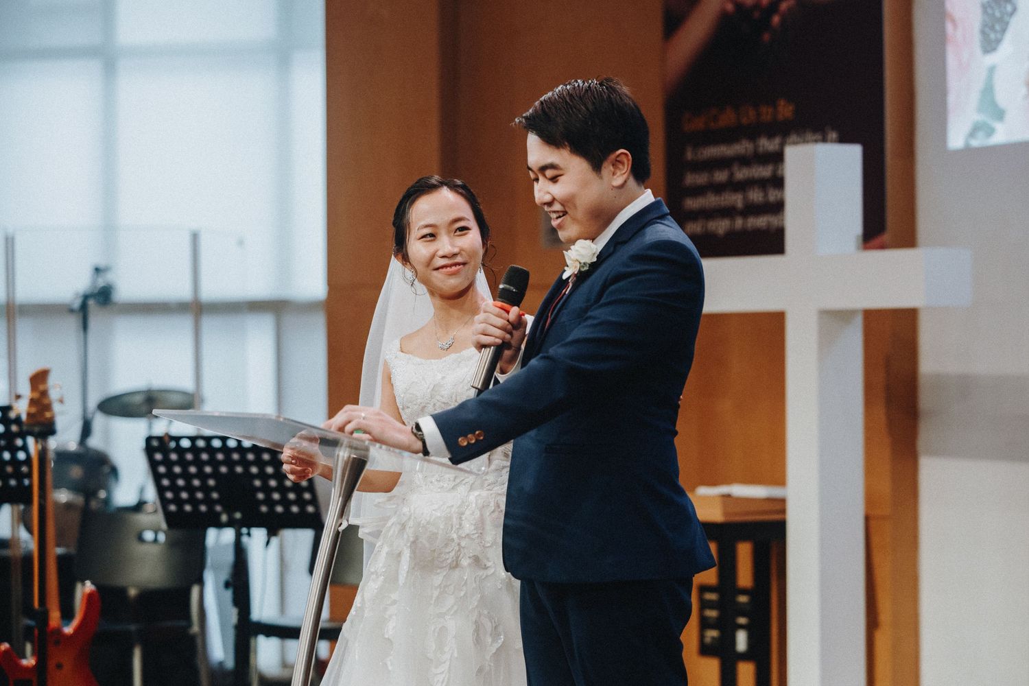 A joyful wedding celebration moment with microphones and music stands visible in the background.