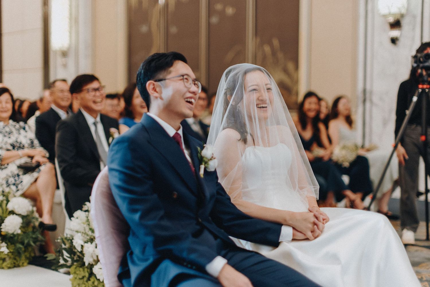 Wedding ceremony guests watch couple during intimate indoor celebration.