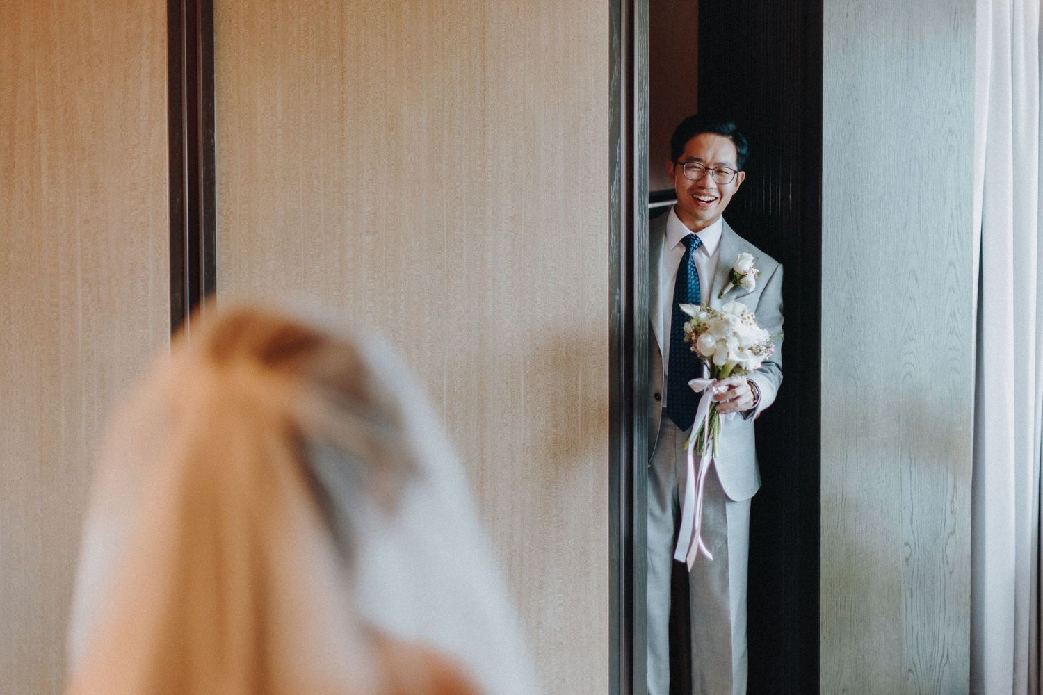 Emotional first look reaction captured through doorway during wedding day.