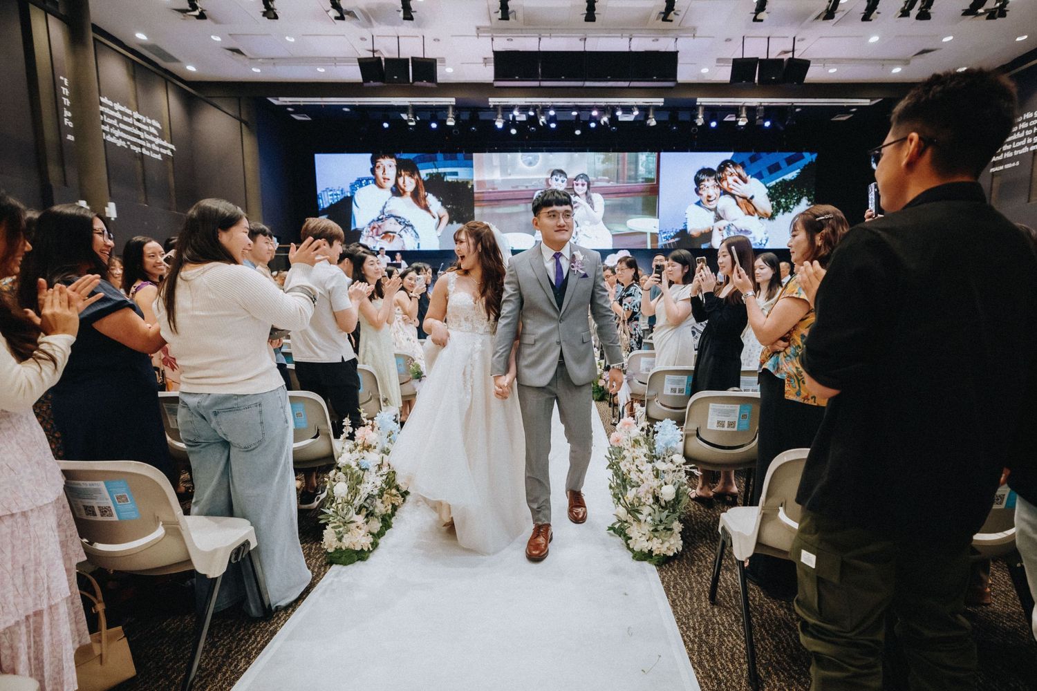 Modern wedding venue interior with white chairs and decorative lighting setup for ceremony.
