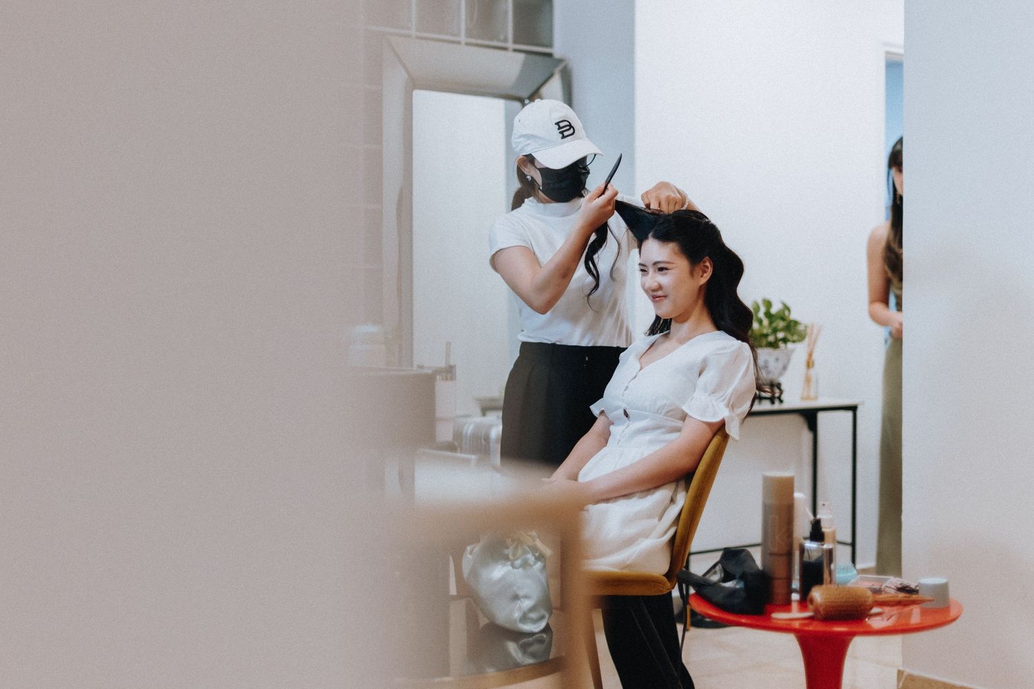 Bride getting hair styled by professional hairstylist in bright salon before wedding ceremony.
