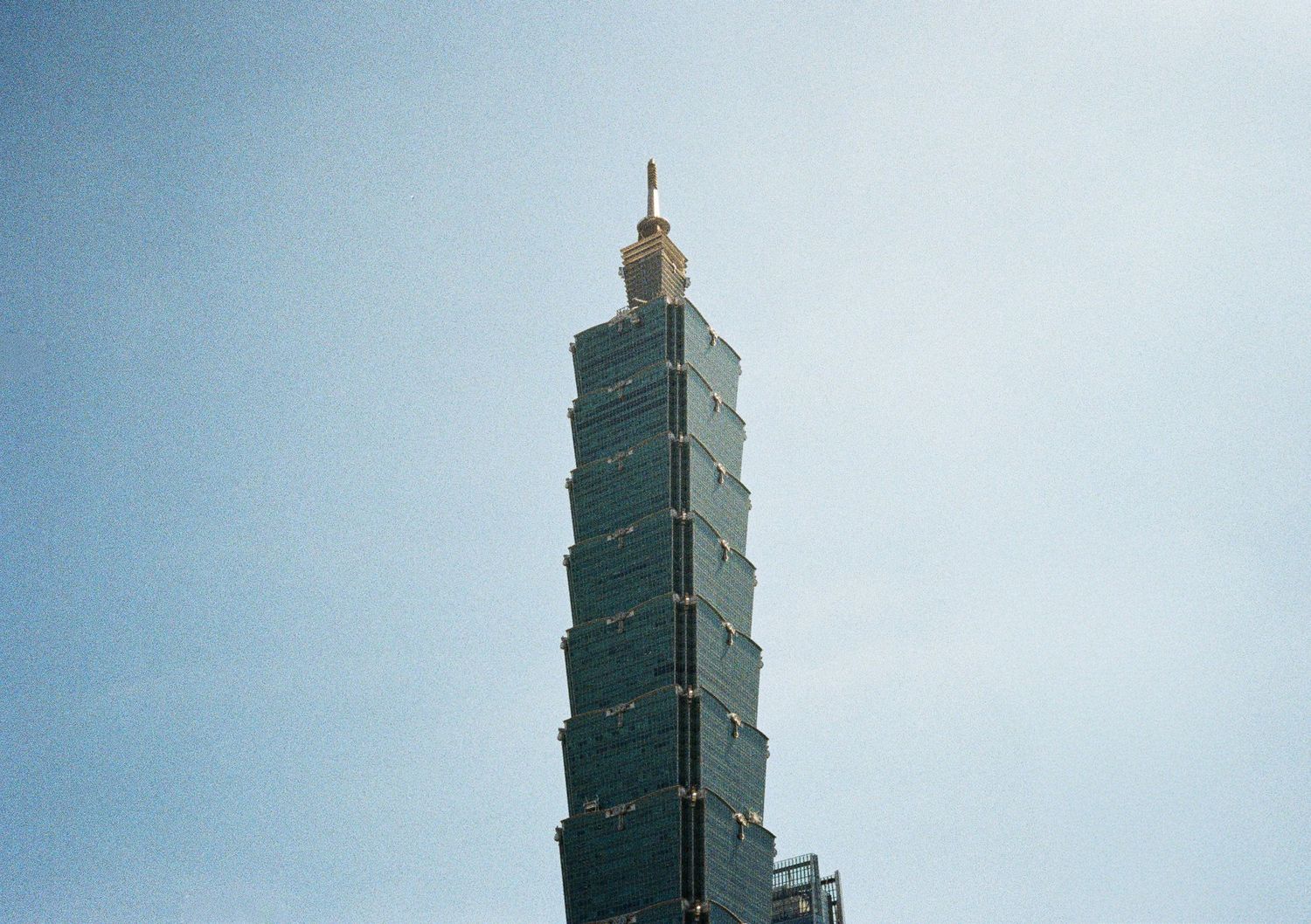 Iconic Taipei 101 skyscraper photographed against light blue sky.