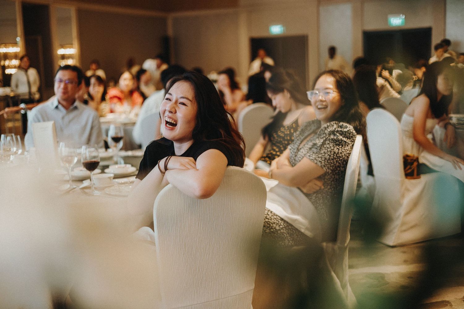 Wedding reception guests seated at tables sharing joyful moments during the celebration.