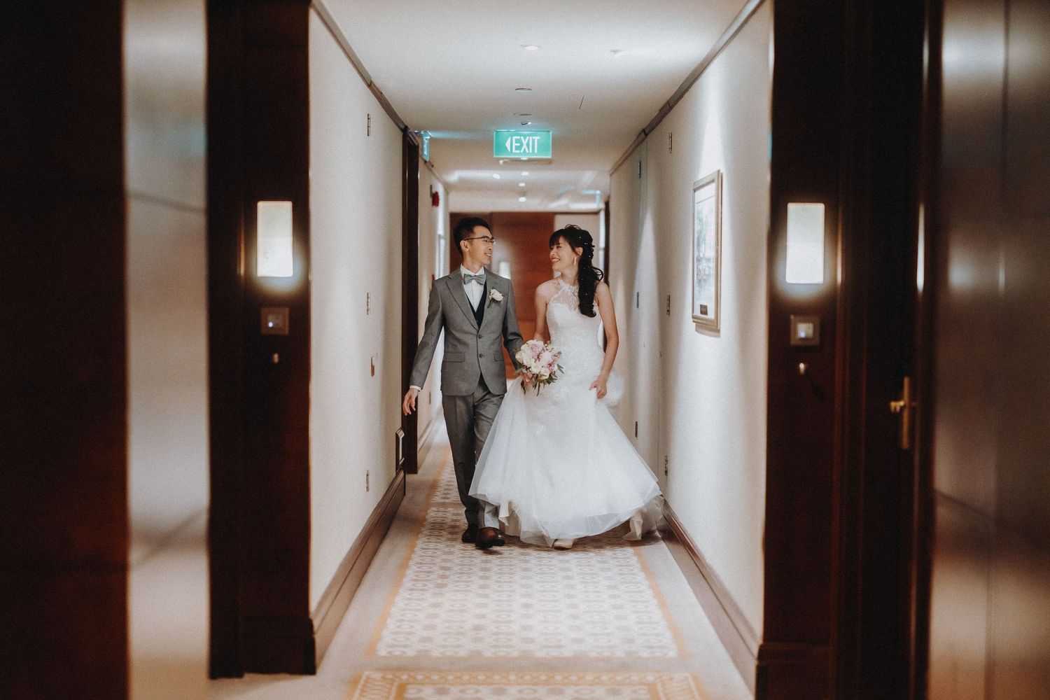 Elegant hotel corridor with wedding dress train flowing down the carpeted hallway.