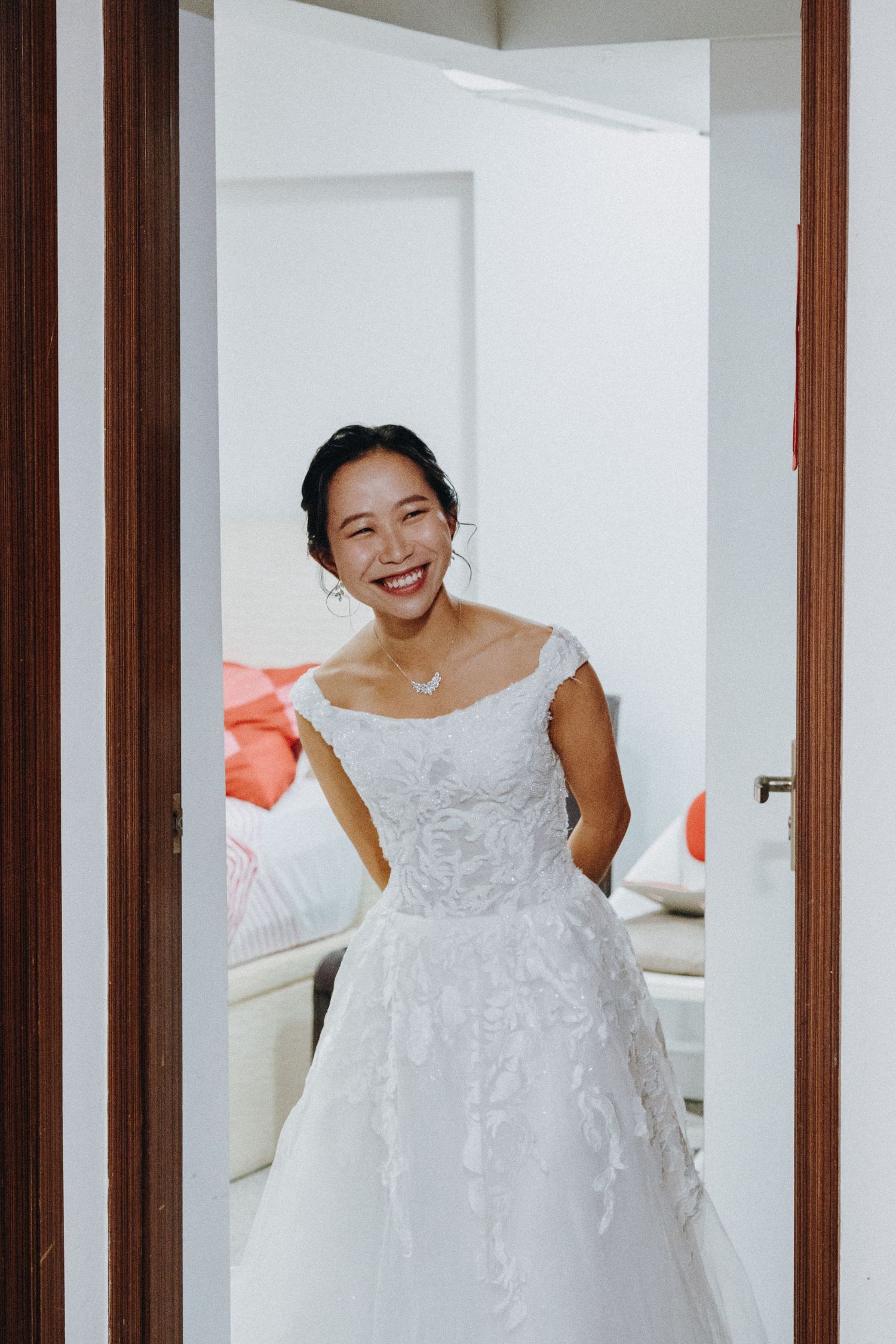 A joyful moment of a bride wearing a white lace wedding dress standing in a doorway.