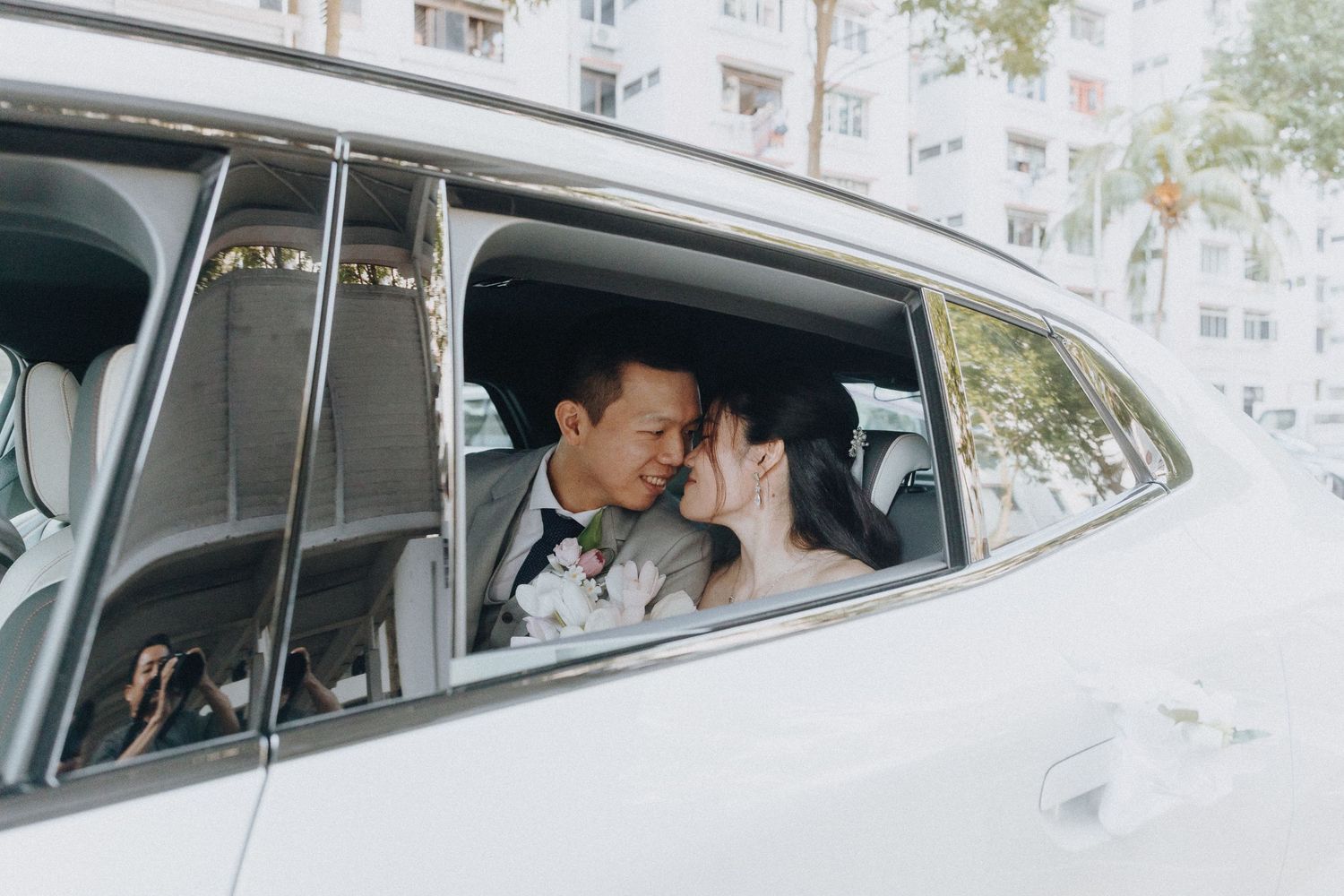 A couple shares an intimate moment in the backseat of a white car.