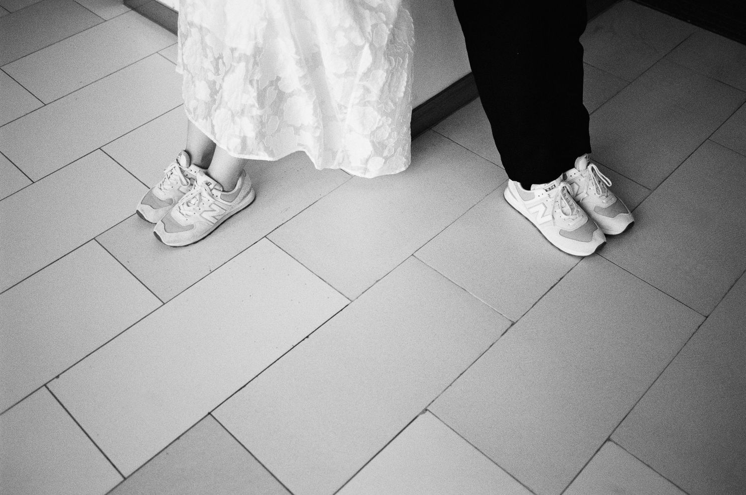 Close-up view of white wedding dress shoes and floor-length gowns at a formal event.