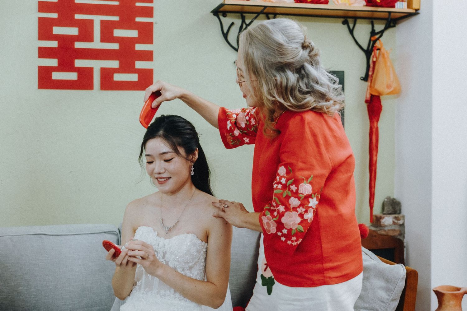 Wedding preparations with red and gold Chinese traditional decor in a bright room.