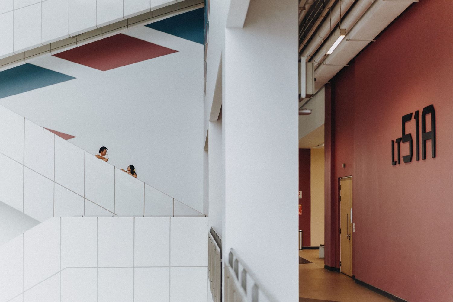 Modern hallway interior with white walls and burgundy accent colors.