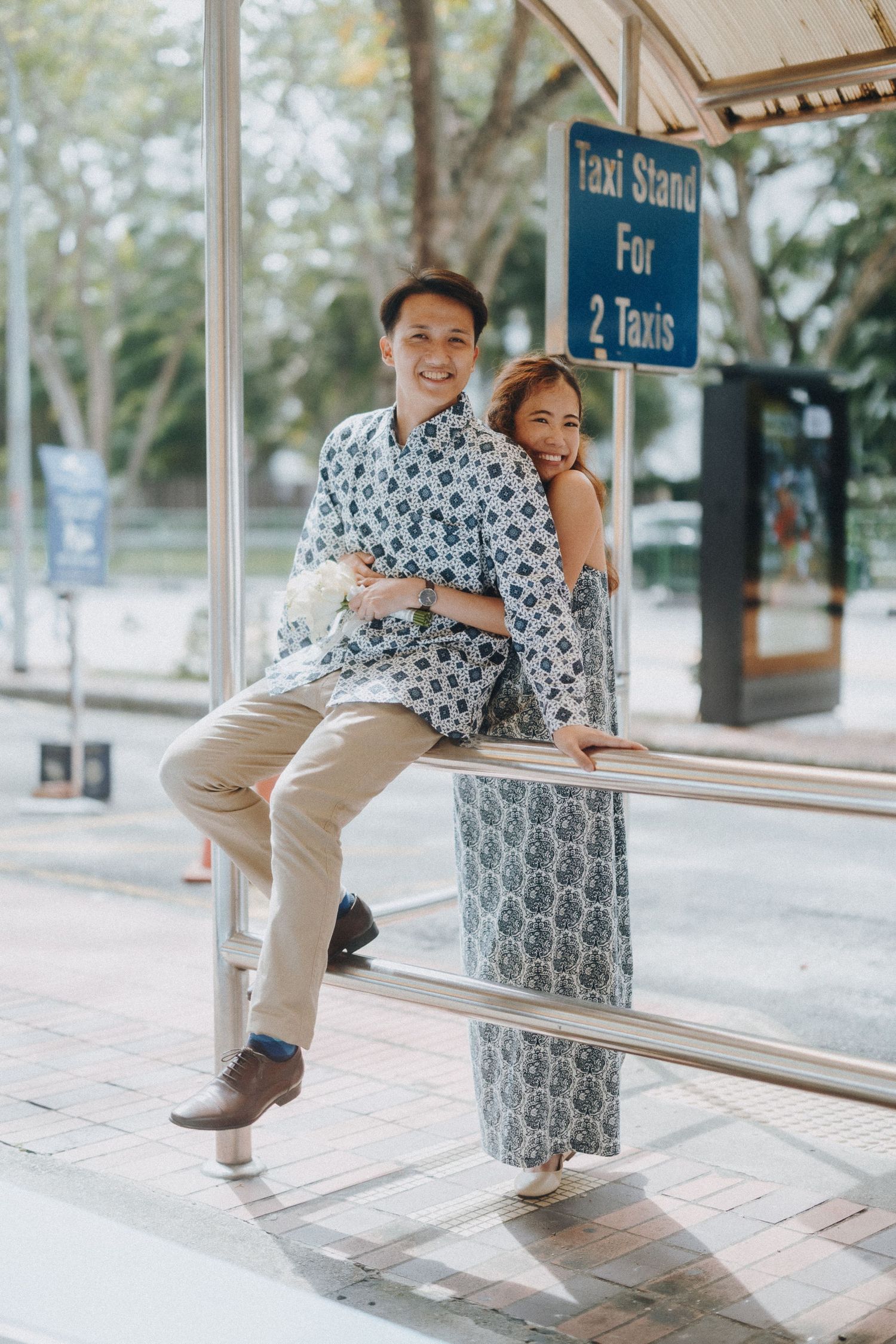 A playful couple shares intimate moments at a covered transit station with vintage architectural details.
