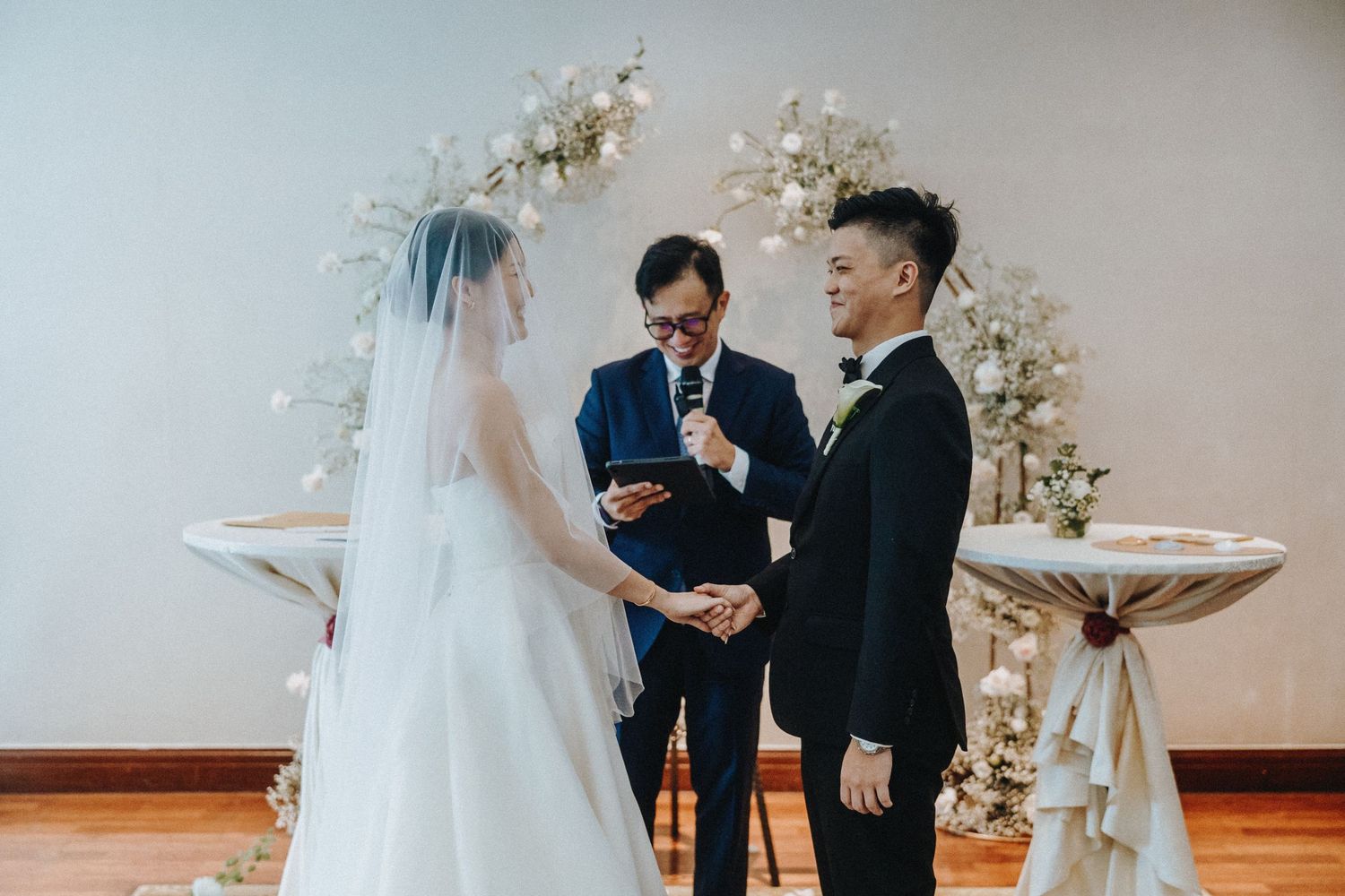Series of wedding ceremony moments captured during vows and ring exchange at an indoor venue.