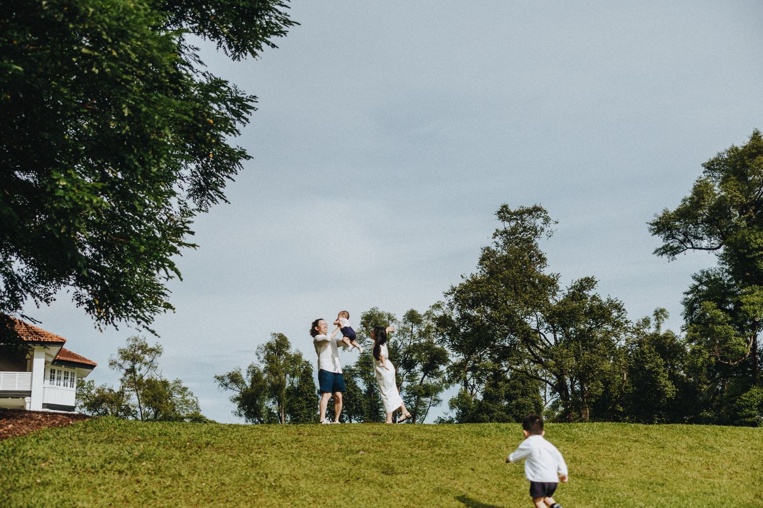 Kids run and play on a grassy hill under cloudy skies during an outdoor gathering.