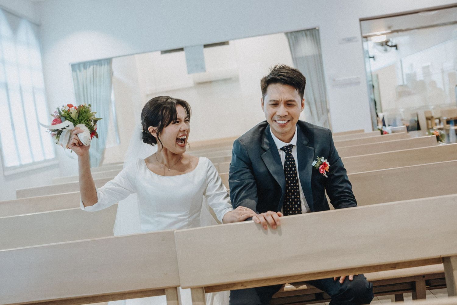 Happy couple in wedding attire celebrating in a church, bride holding bouquet and groom in suit smiling joyfully.