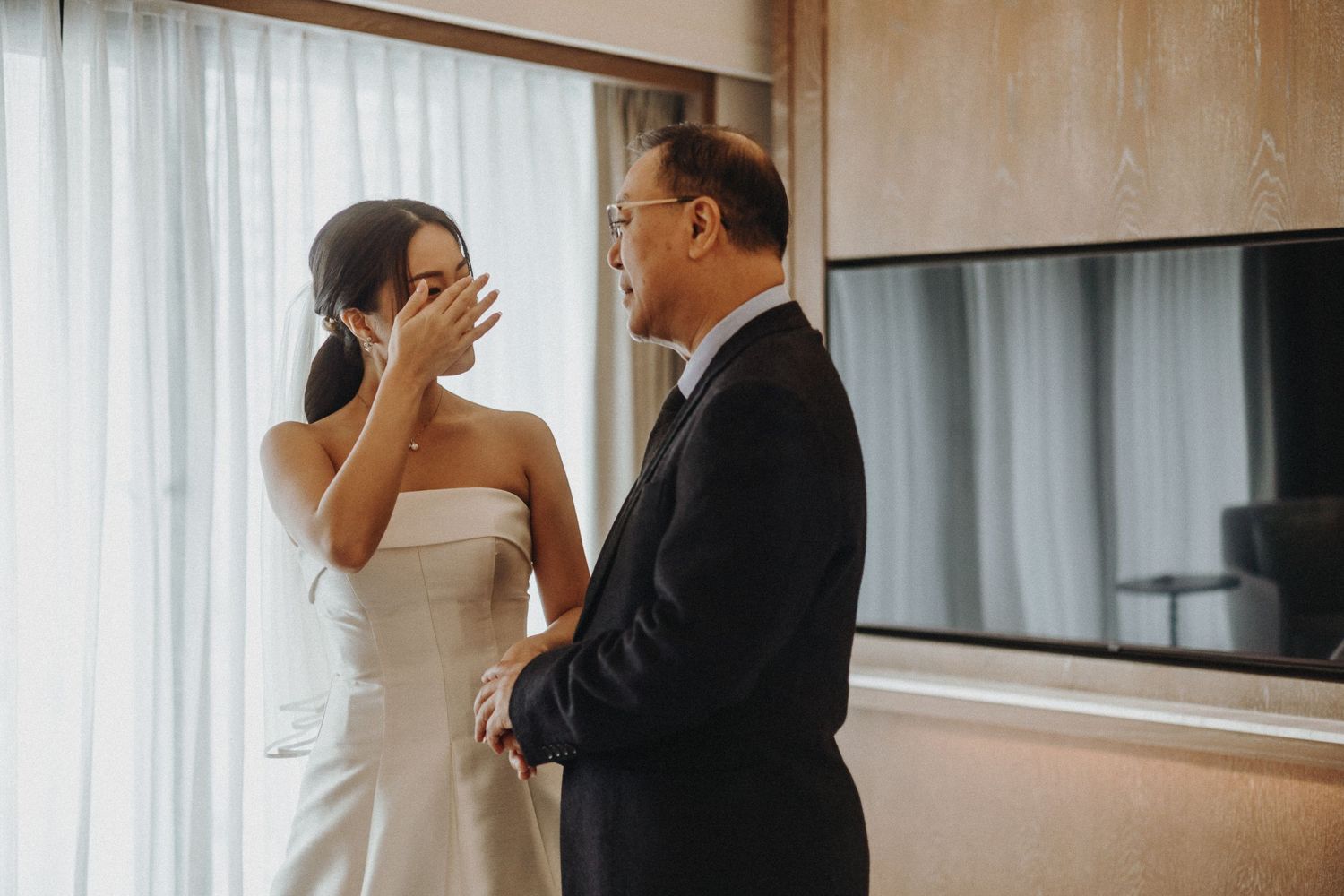 Elegant couple posing near white curtained windows during their first look photo session.