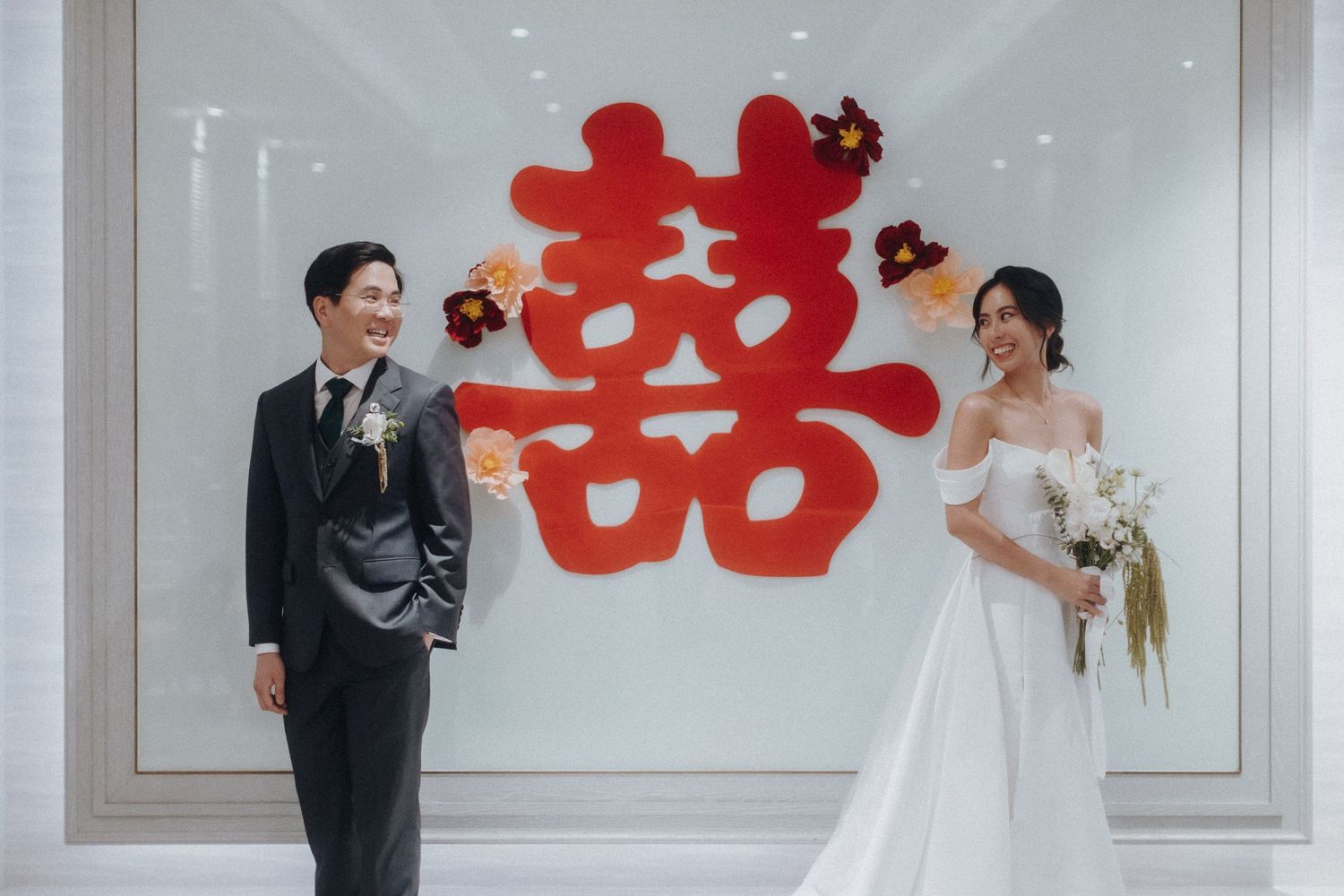 Bride and groom share a romantic first dance in an elegant wedding venue decorated with red Chinese double happiness symbols.