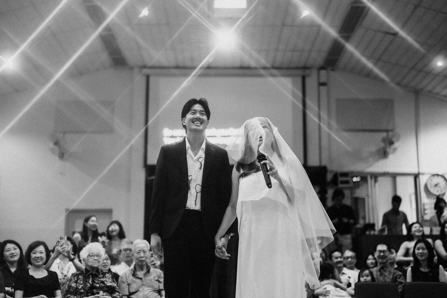 Black and white photo of newlyweds standing together during indoor ceremony.
