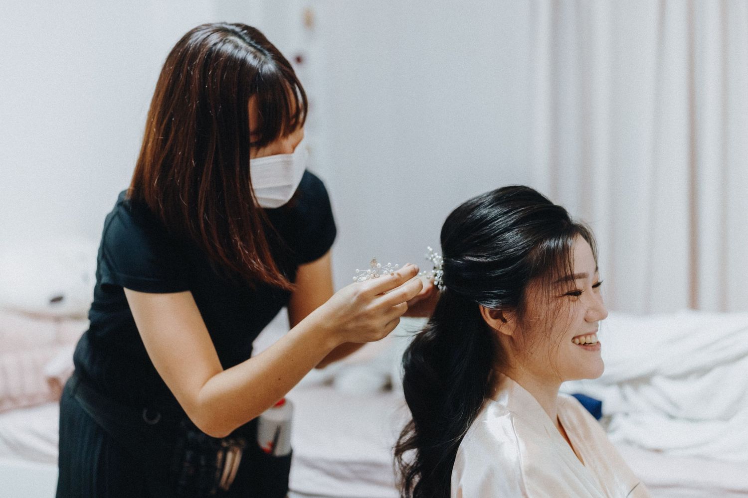 Professional hairstylist working on a client's dark hair in a bright salon setting.