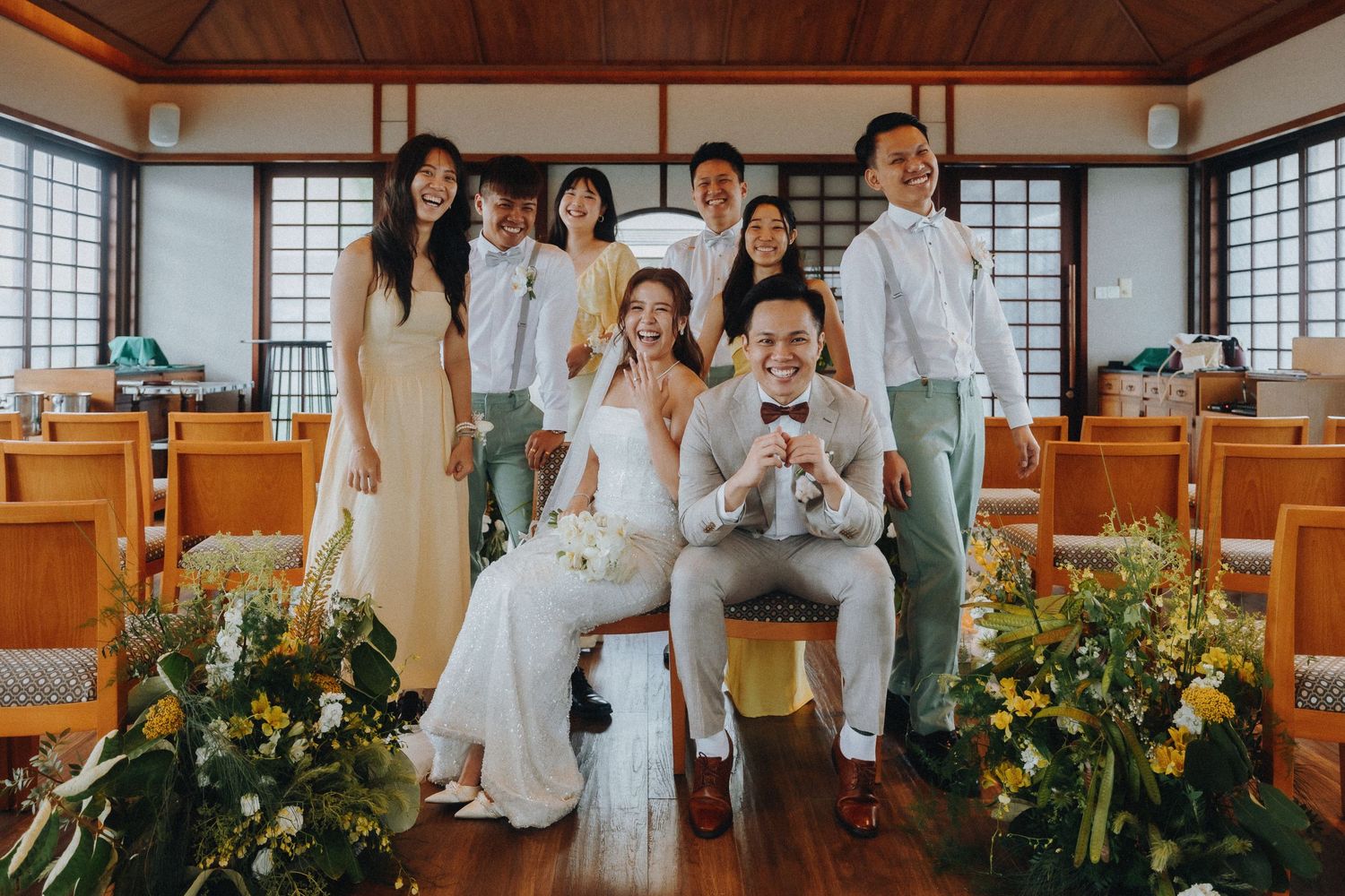 Wedding party group photo in Japanese style room with yellow floral decorations.