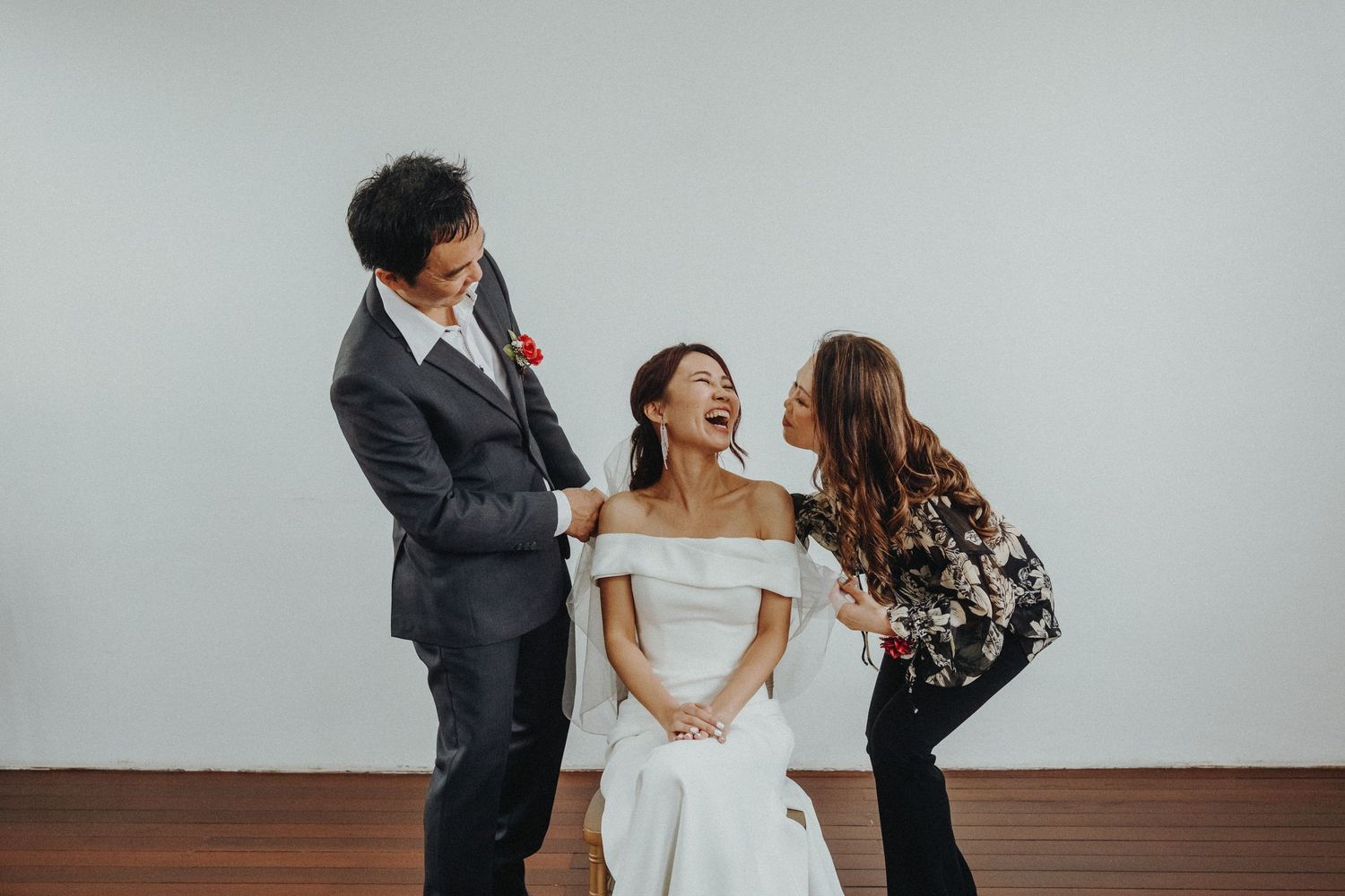 A joyful candid moment during a formal event with people dancing together against a white wall backdrop.