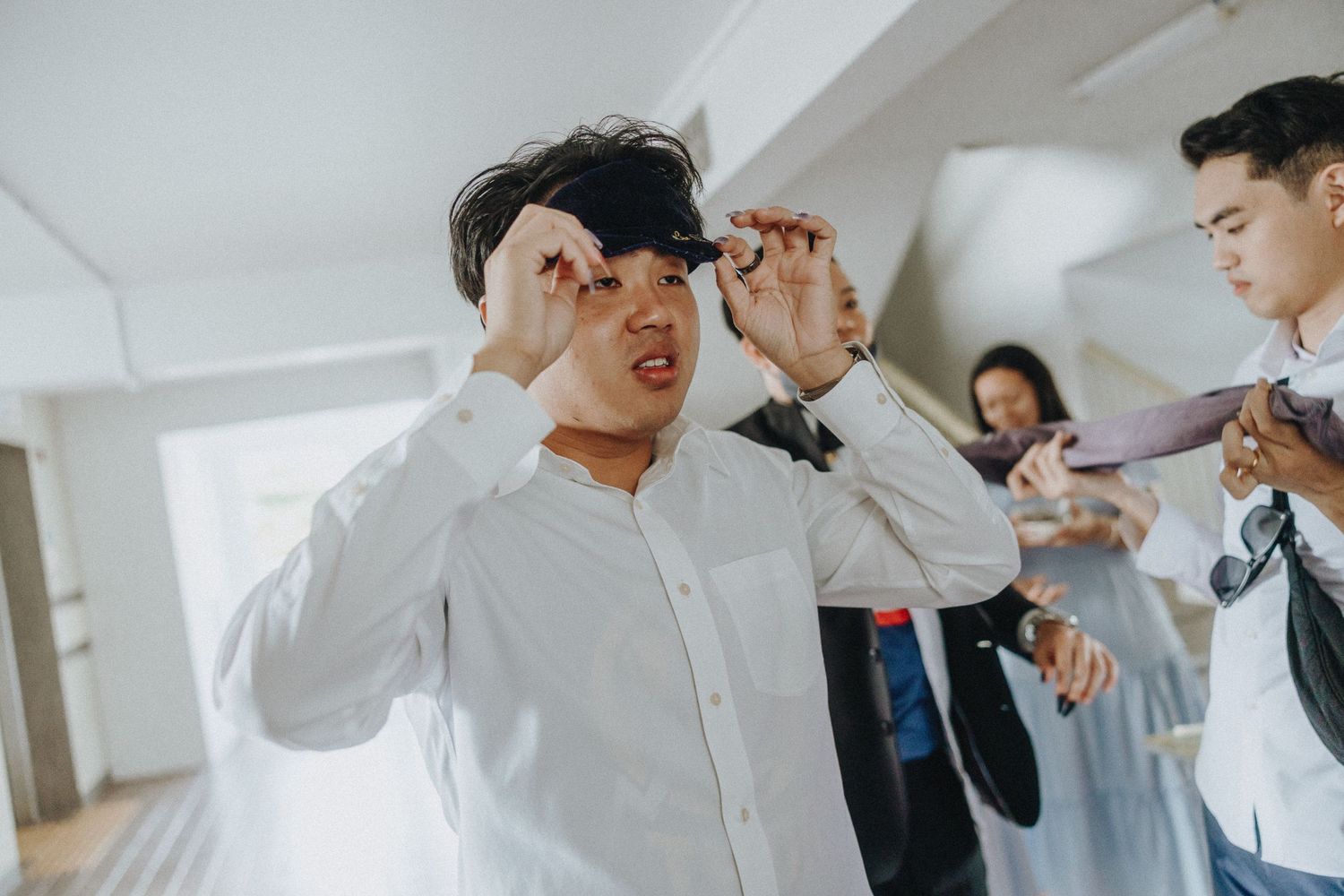 People getting ready in a bright indoor space with someone adjusting their cap.
