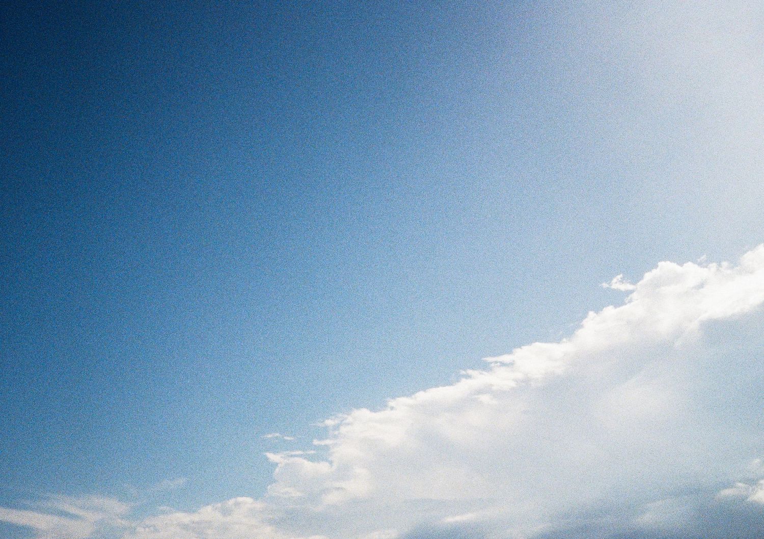 Panoramic view of a bright blue sky with scattered white clouds during daytime.