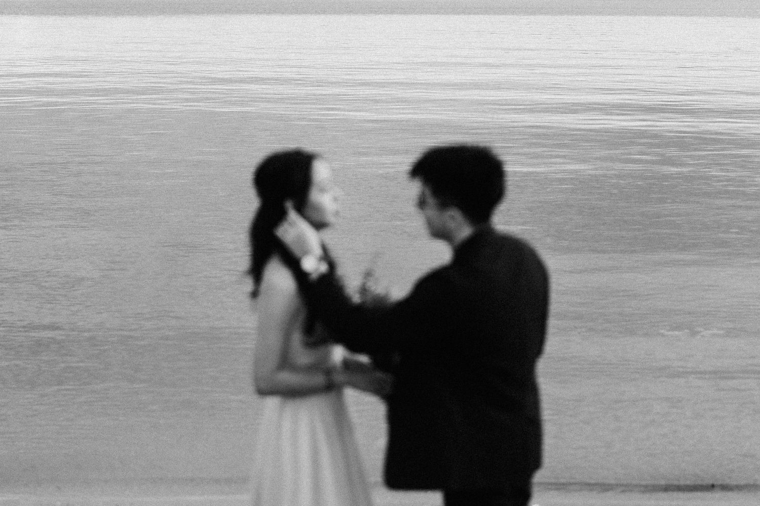 A romantic black and white silhouette shows two figures standing together on a beach at dusk.