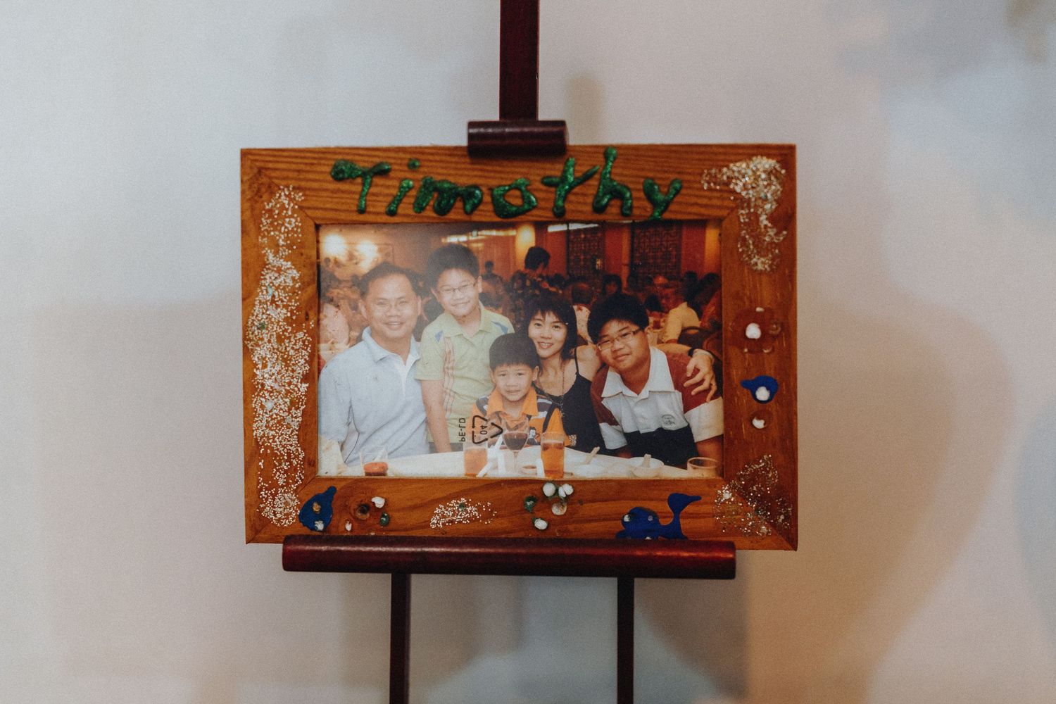 Brown wooden display stand showcasing framed decorative artwork.