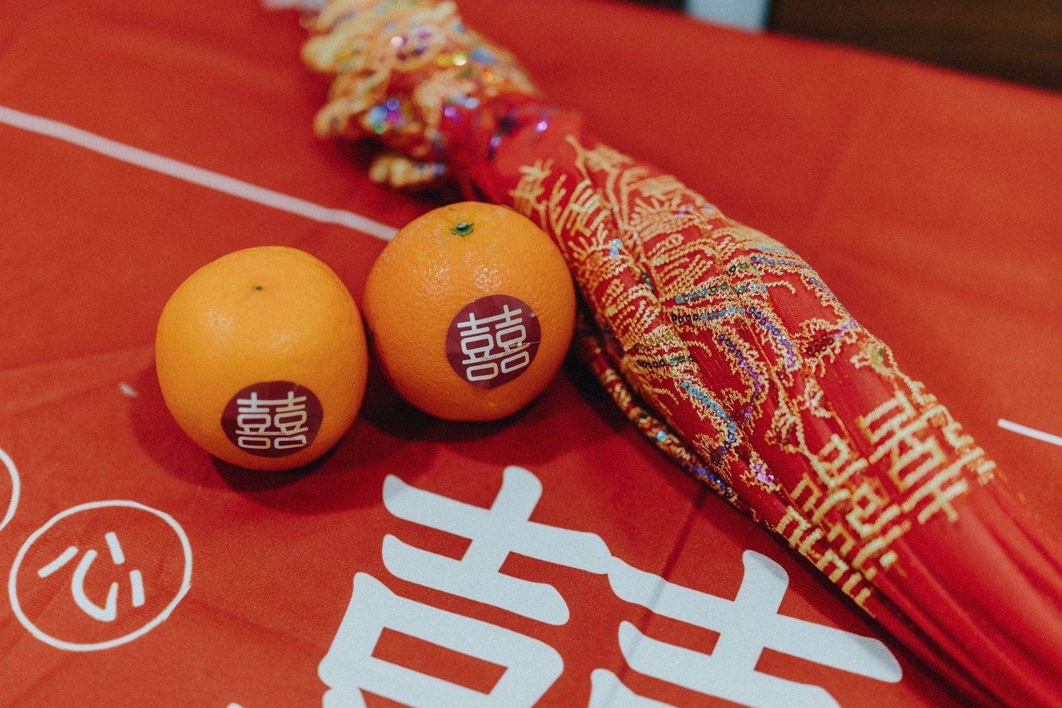 Traditional Chinese New Year decorations with red envelopes and mandarin oranges arranged on a red surface.
