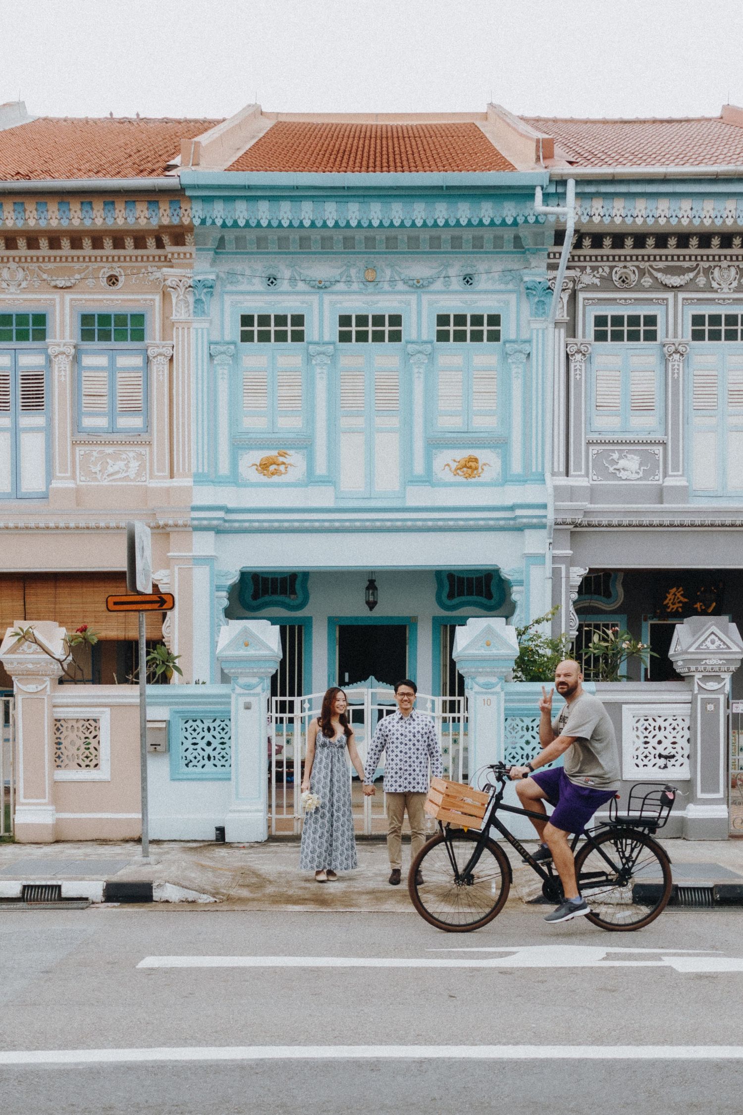 Row of colorful pastel Peranakan shophouses with ornate architectural details in Singapore featuring a vintage bicycle.