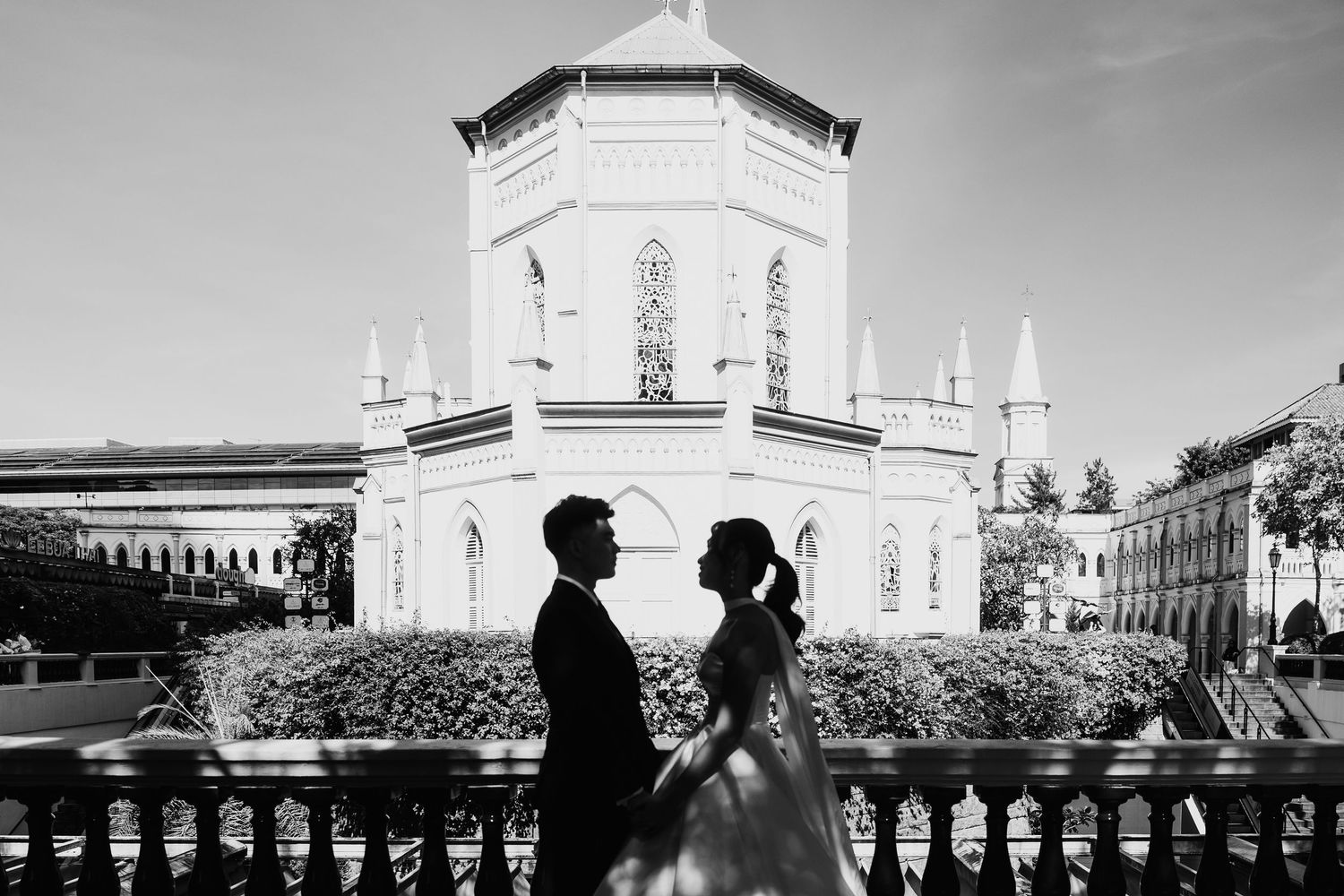 Bride and groom silhouette in front of a grand white church in black and white.