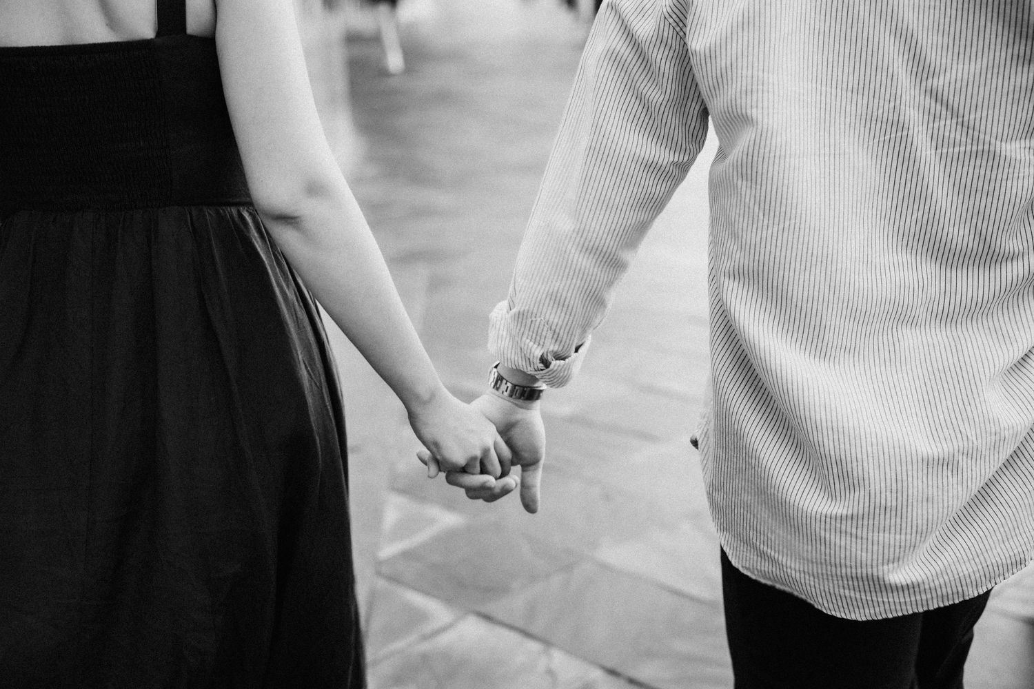 Black and white photo of a couple holding hands while walking together.