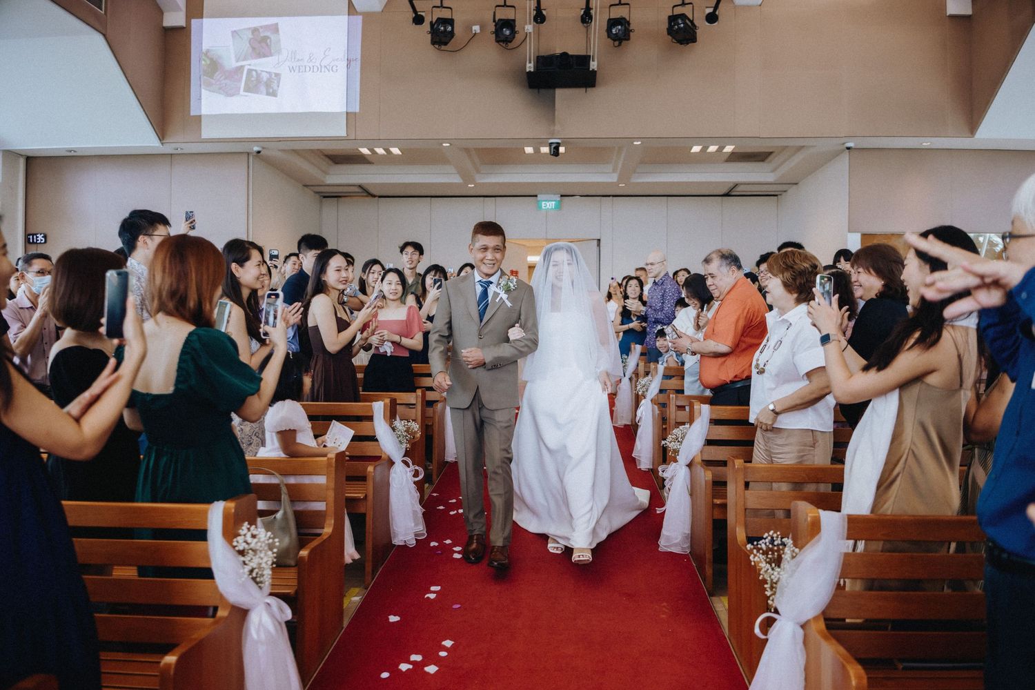 Bride and groom walking down the aisle at a church wedding ceremony with guests applauding.