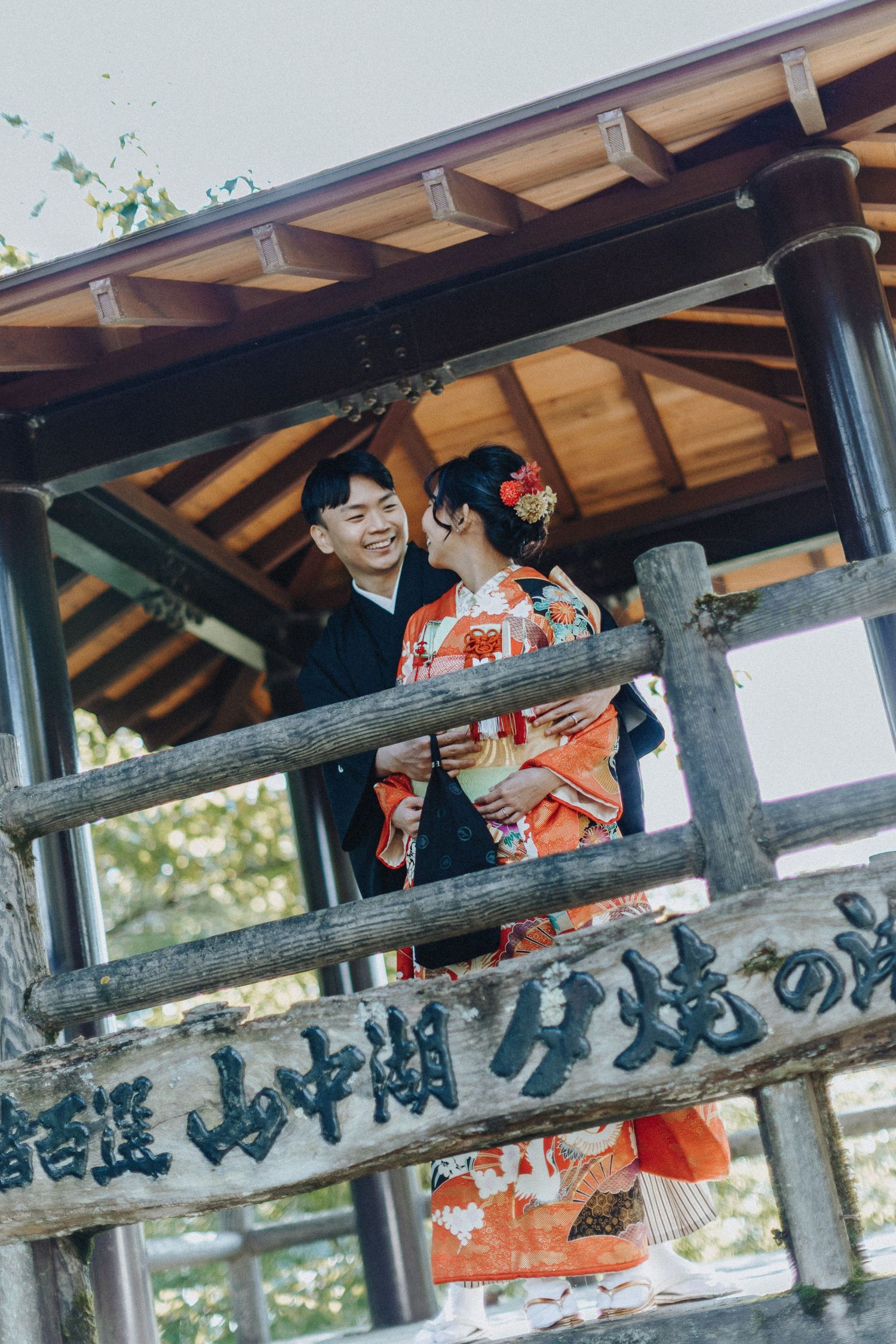 A couple in traditional Japanese attire standing on a wooden walkway at a temple.