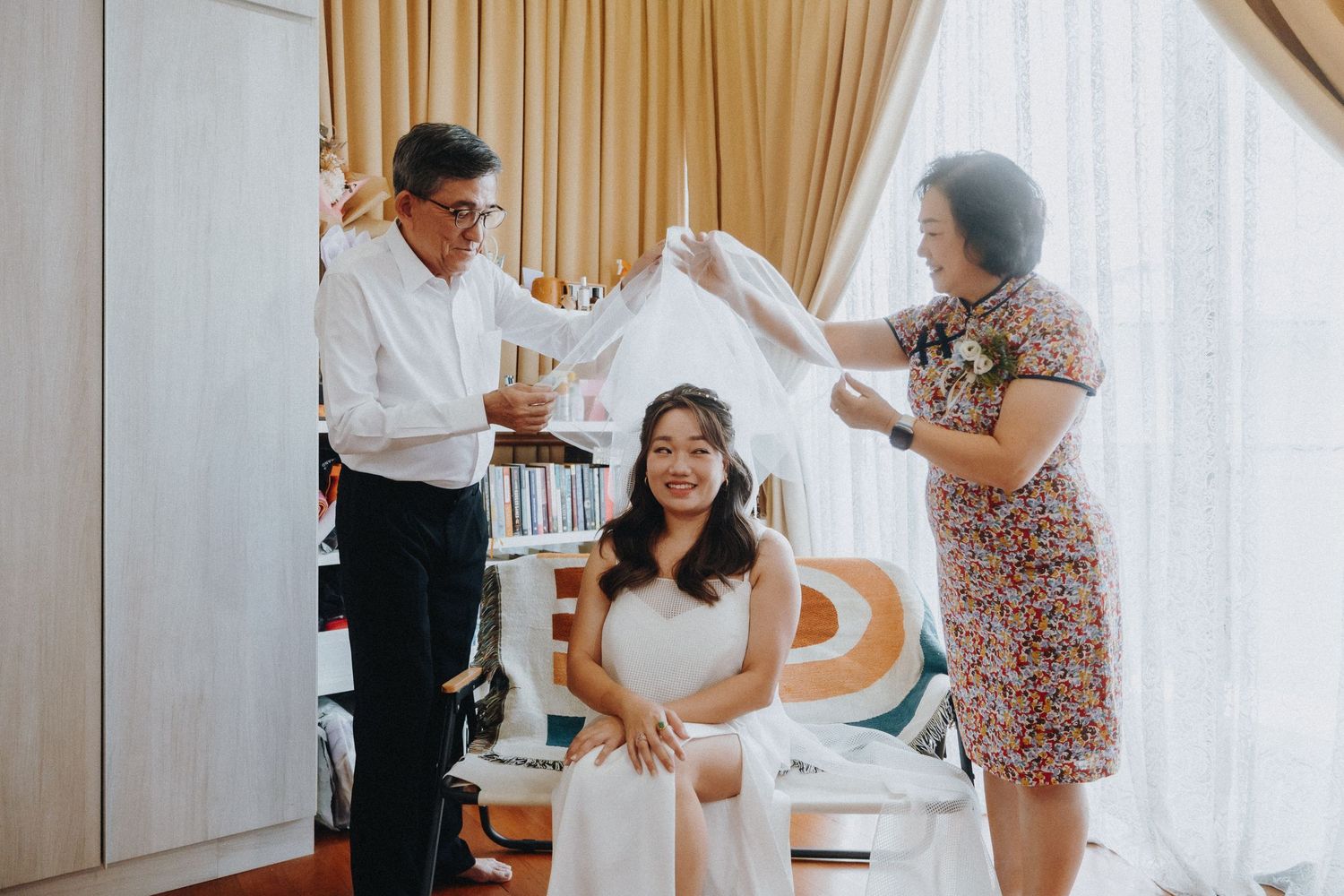 A preparation scene with attendants helping adjust a white dress.