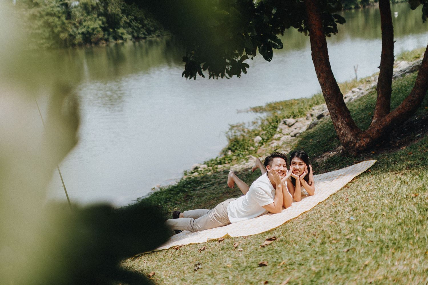 Couple relaxing by a serene lake surrounded by lush greenery.