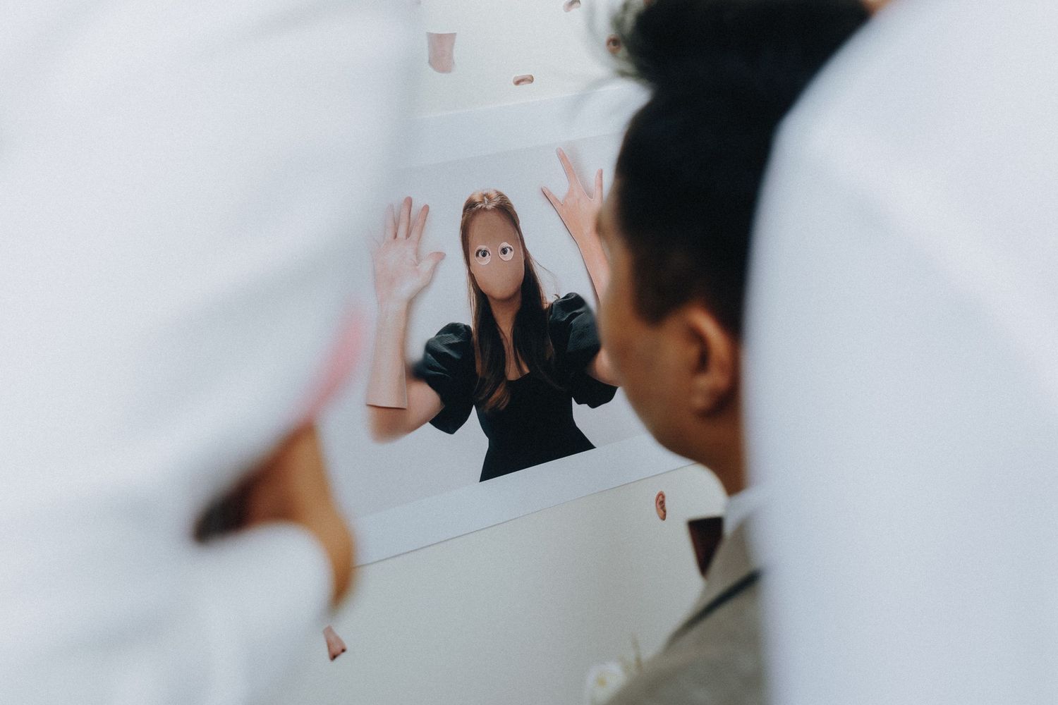 A reflection in a mirror shows a person gesturing expressively with raised hands.