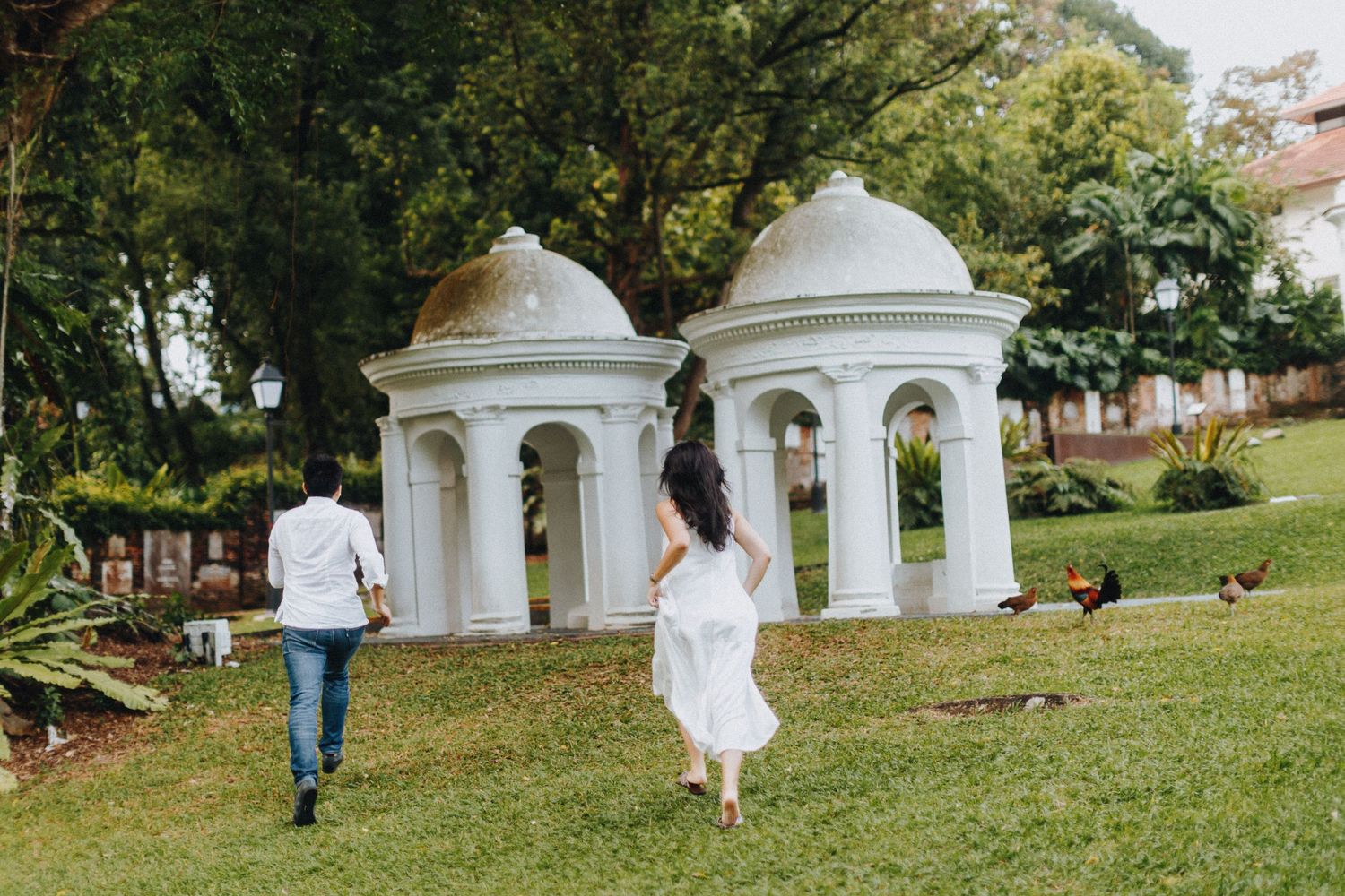 Two domed gazebos stand on a grassy hill while people walk near them on a sunny day.