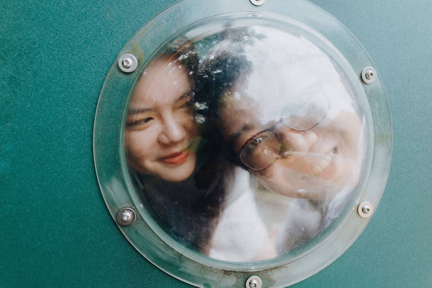 A series of circular porthole windows showing a person and pet cat looking through the glass.