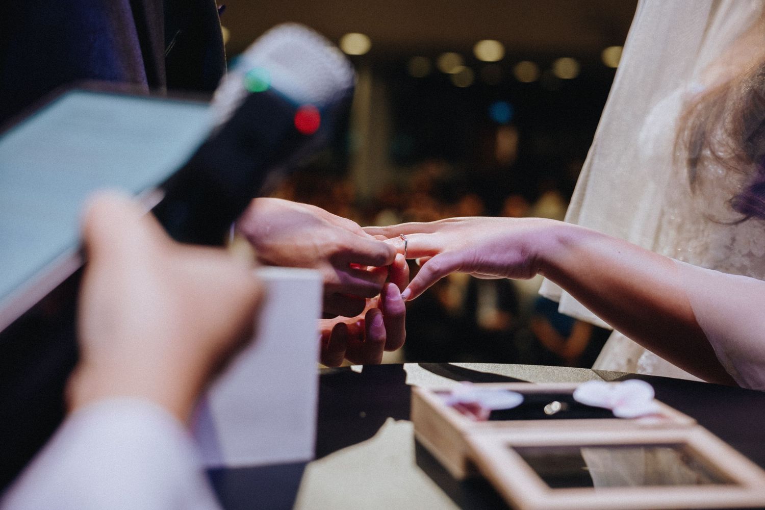 Close-up of hands exchanging rings during a wedding ceremony.