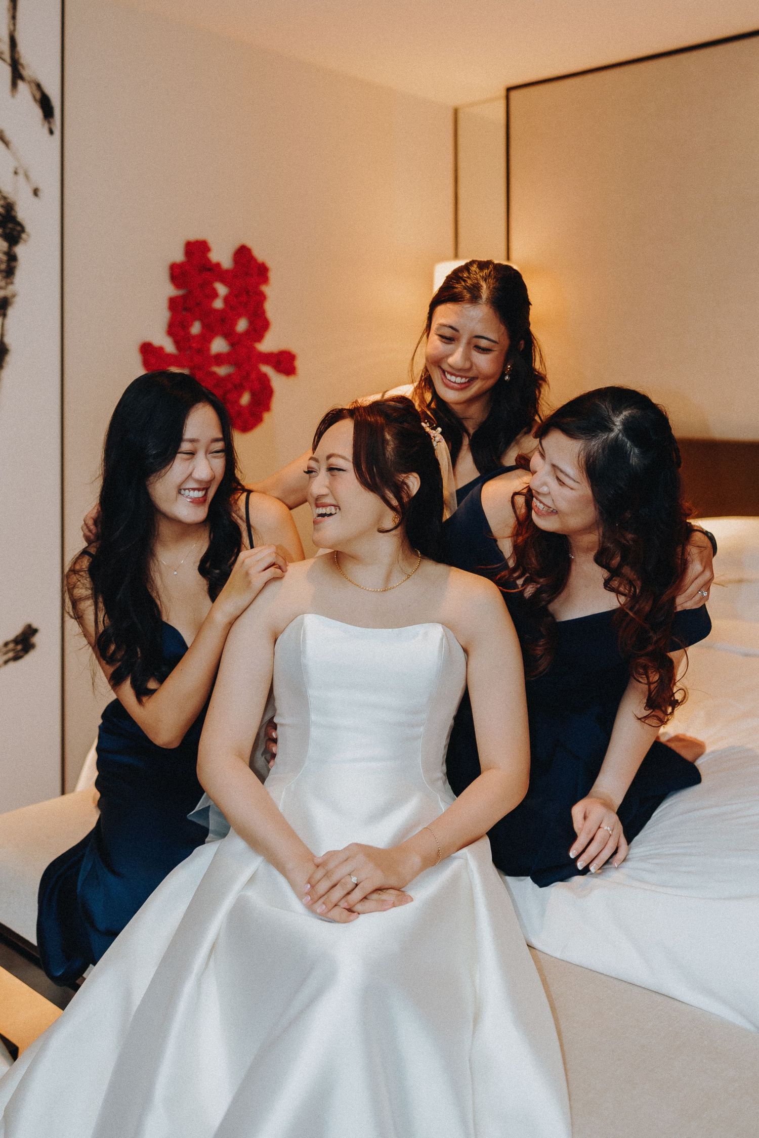 Bridesmaids in black dresses gather around a bride in a white gown sharing joyful moments.