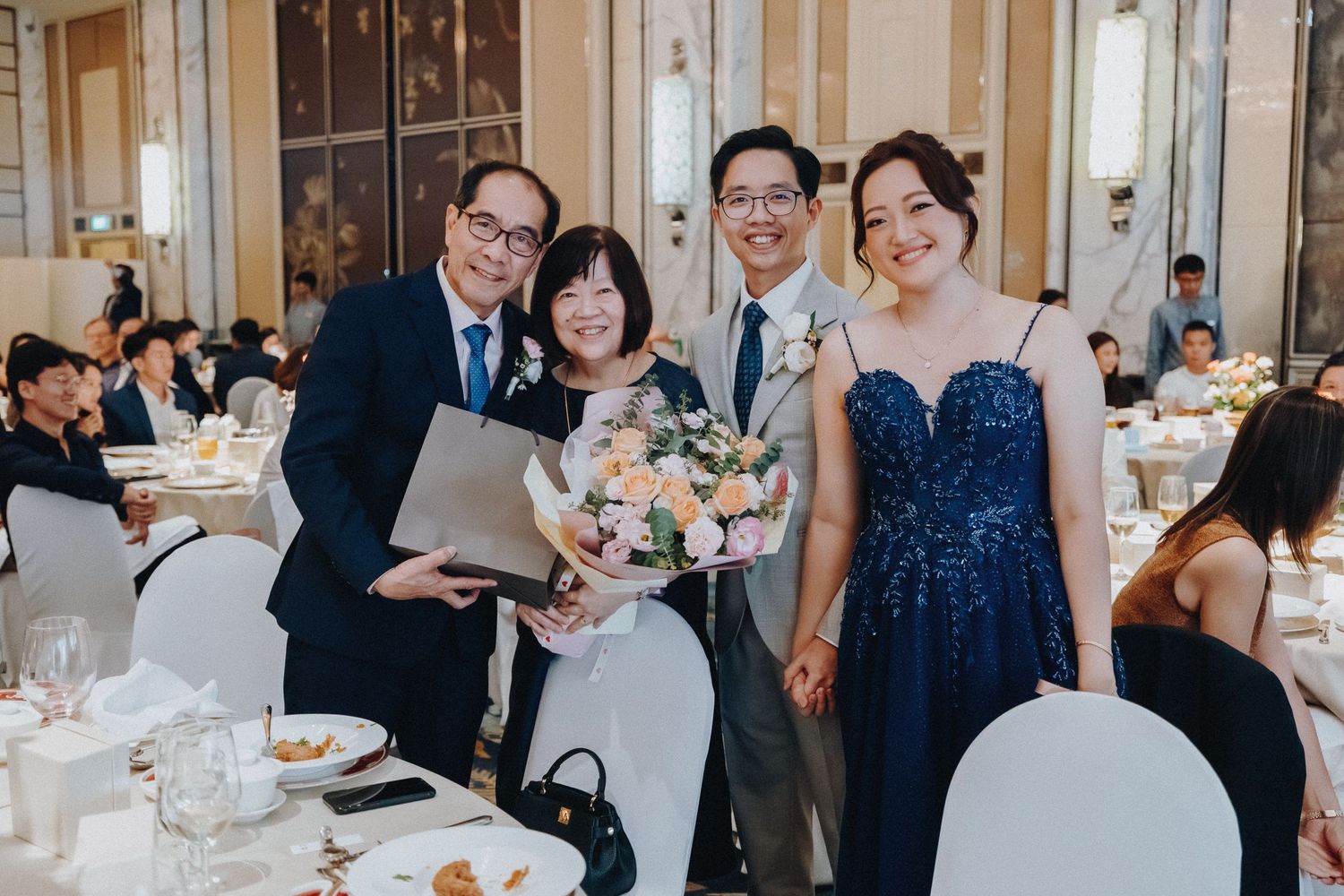 Formal wedding reception gathering with guests in navy and formal attire at an elegant banquet table.