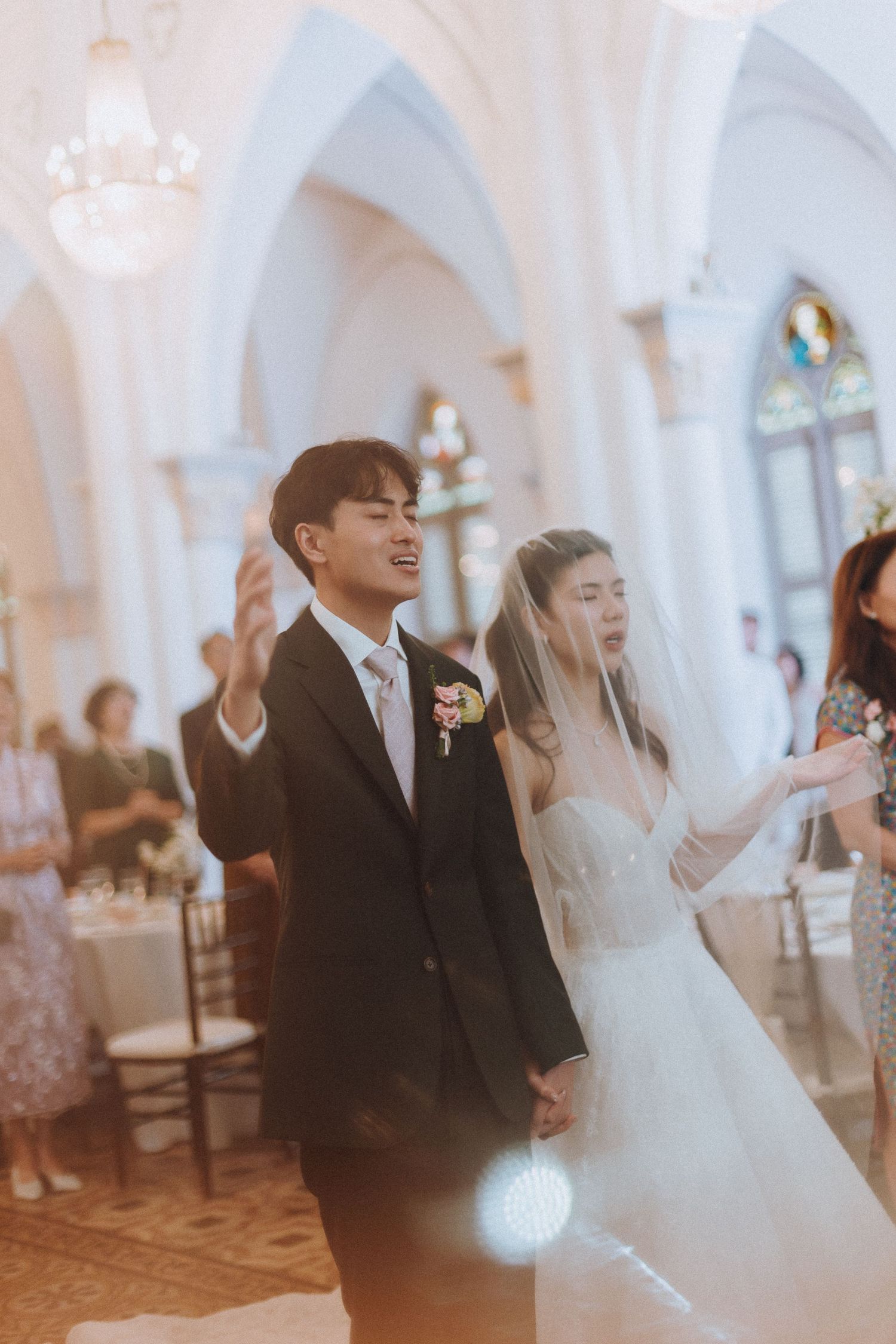 Bride and groom share a joyful moment dancing together in an elegant white arched wedding venue.