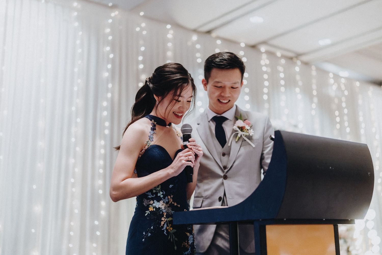 Wedding reception venue with fairy light backdrop and guests in formal attire.