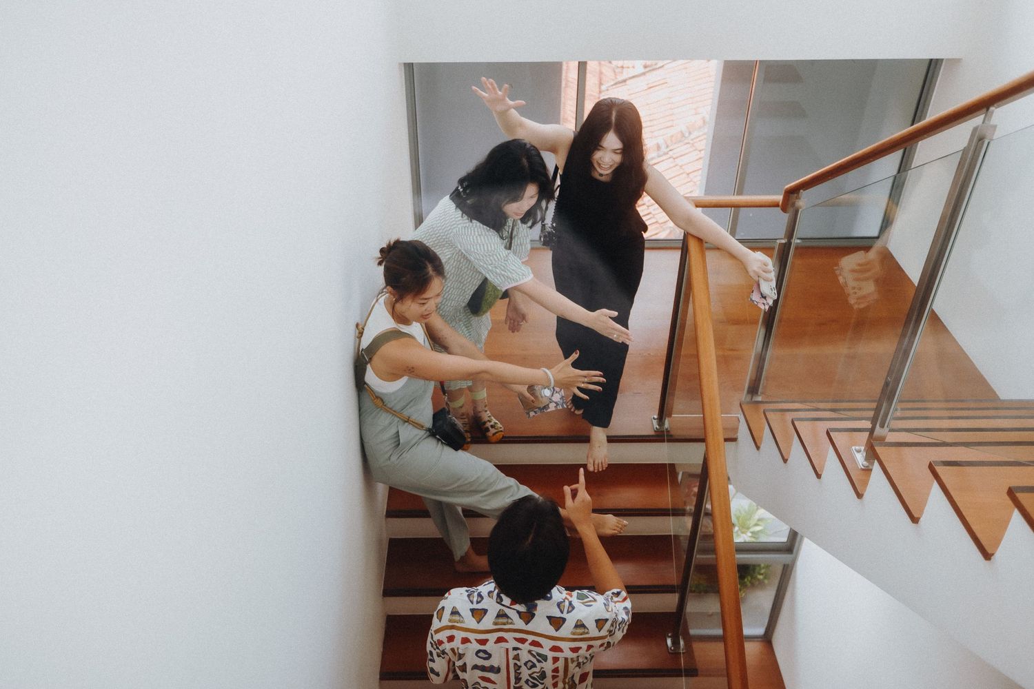 Group of people sitting together on modern wooden stairs having casual conversation in office building.