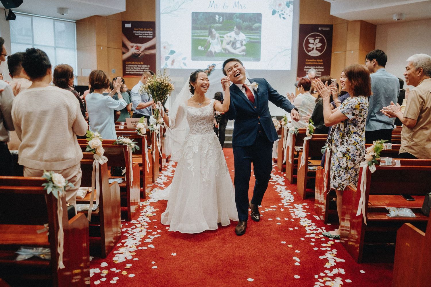 Wedding ceremony in a church with flower petals lining the red carpet aisle.