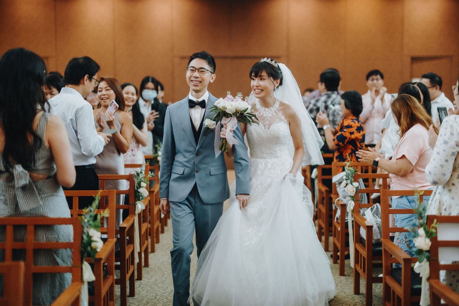 Wedding ceremony in a church with wooden pews and guests in attendance.