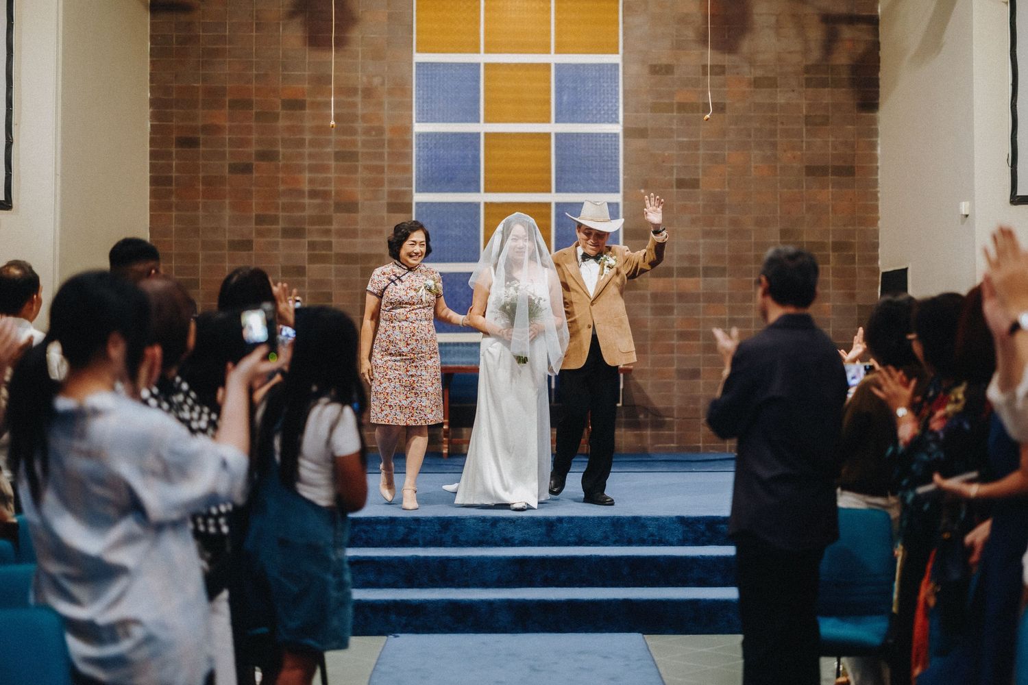 Wedding guests celebrate and take photos during the ceremony in a chapel.