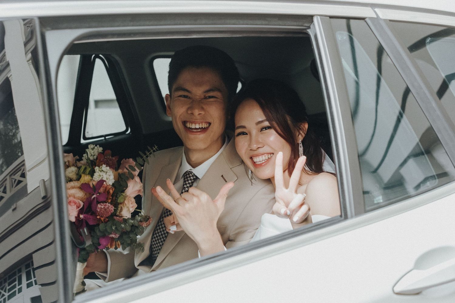 Wedding party smiling and celebrating inside a white car.