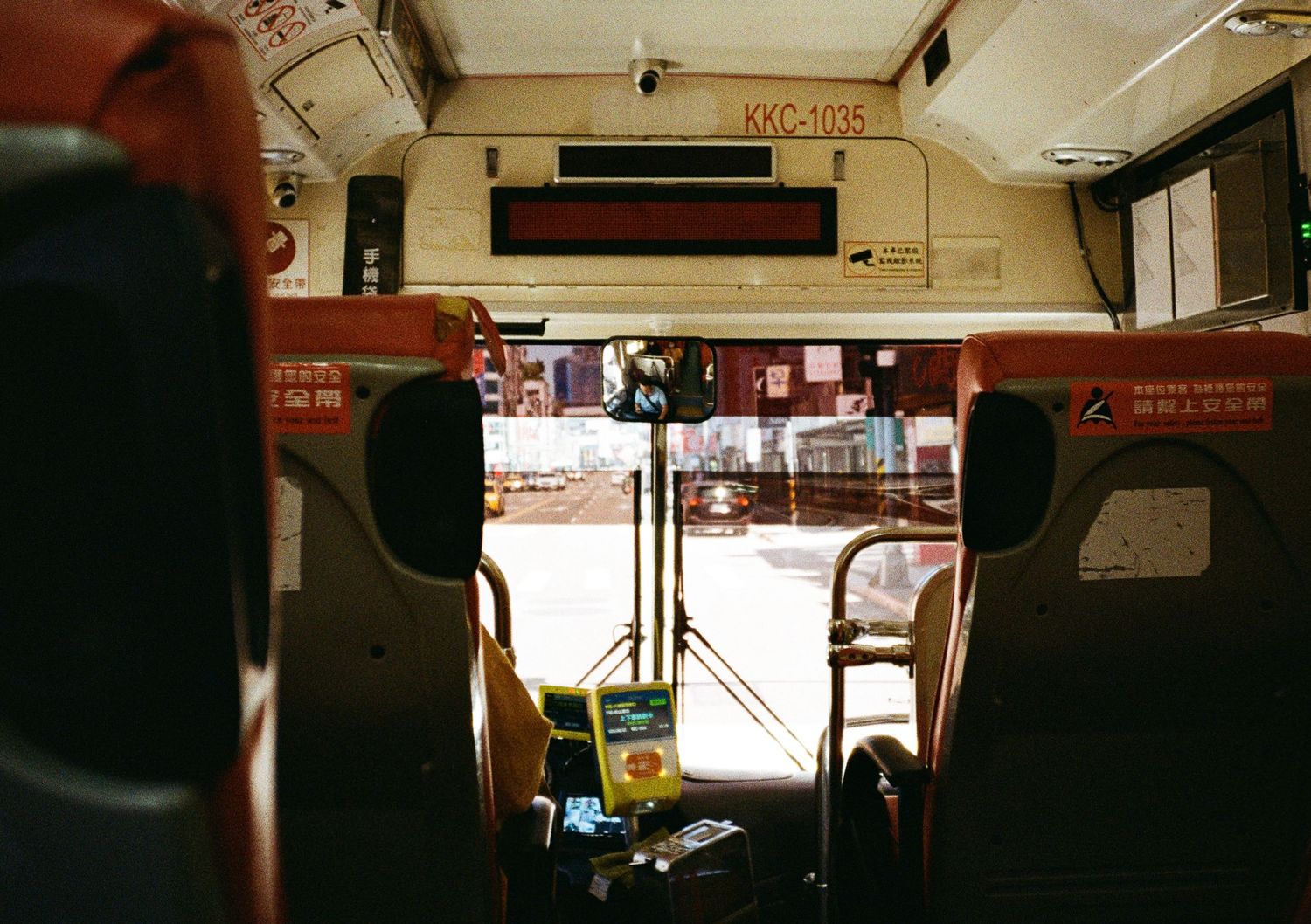 Interior of a dimly lit public transit vehicle showing seats and windows.