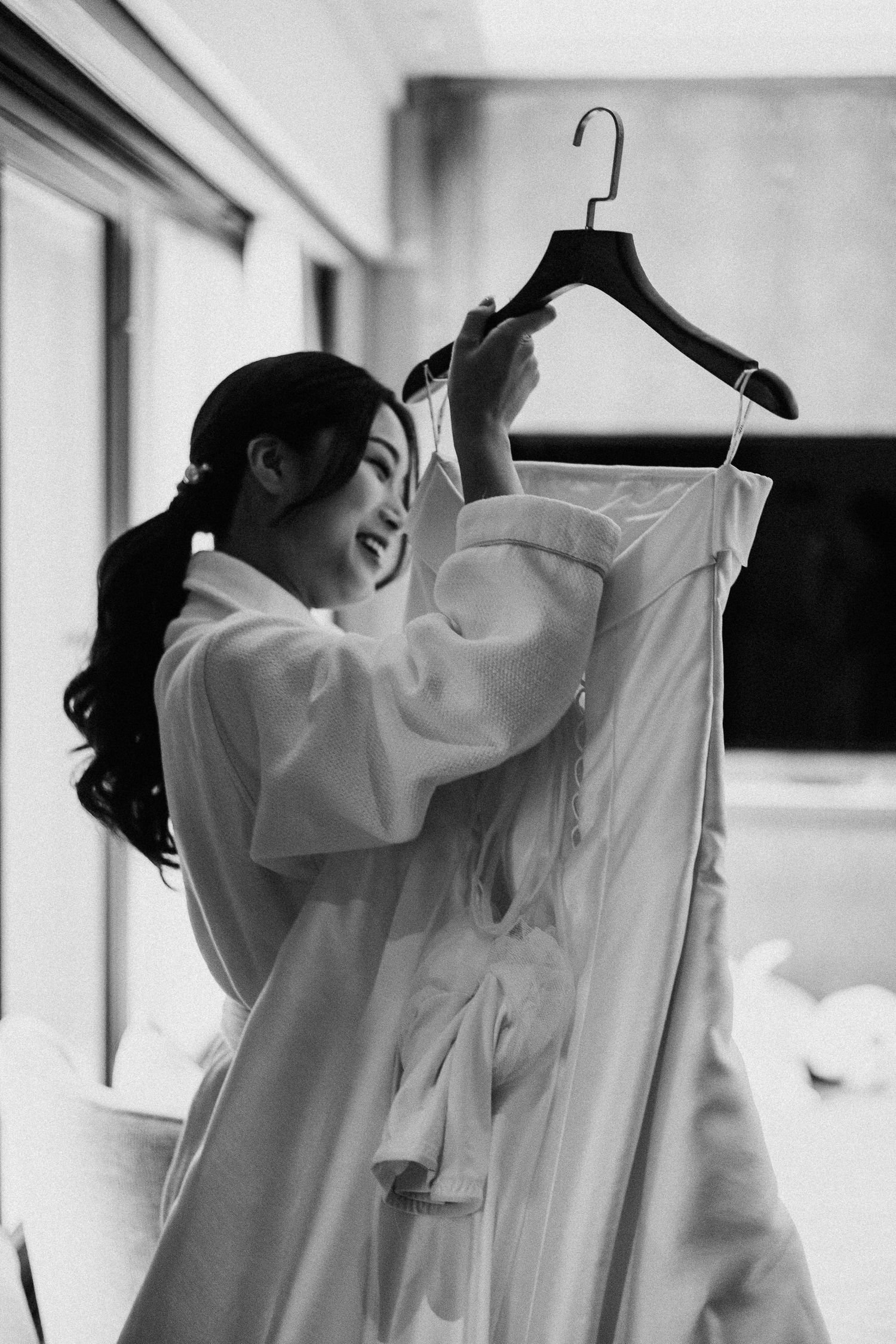 A black and white photo of someone in a robe preparing wedding attire.